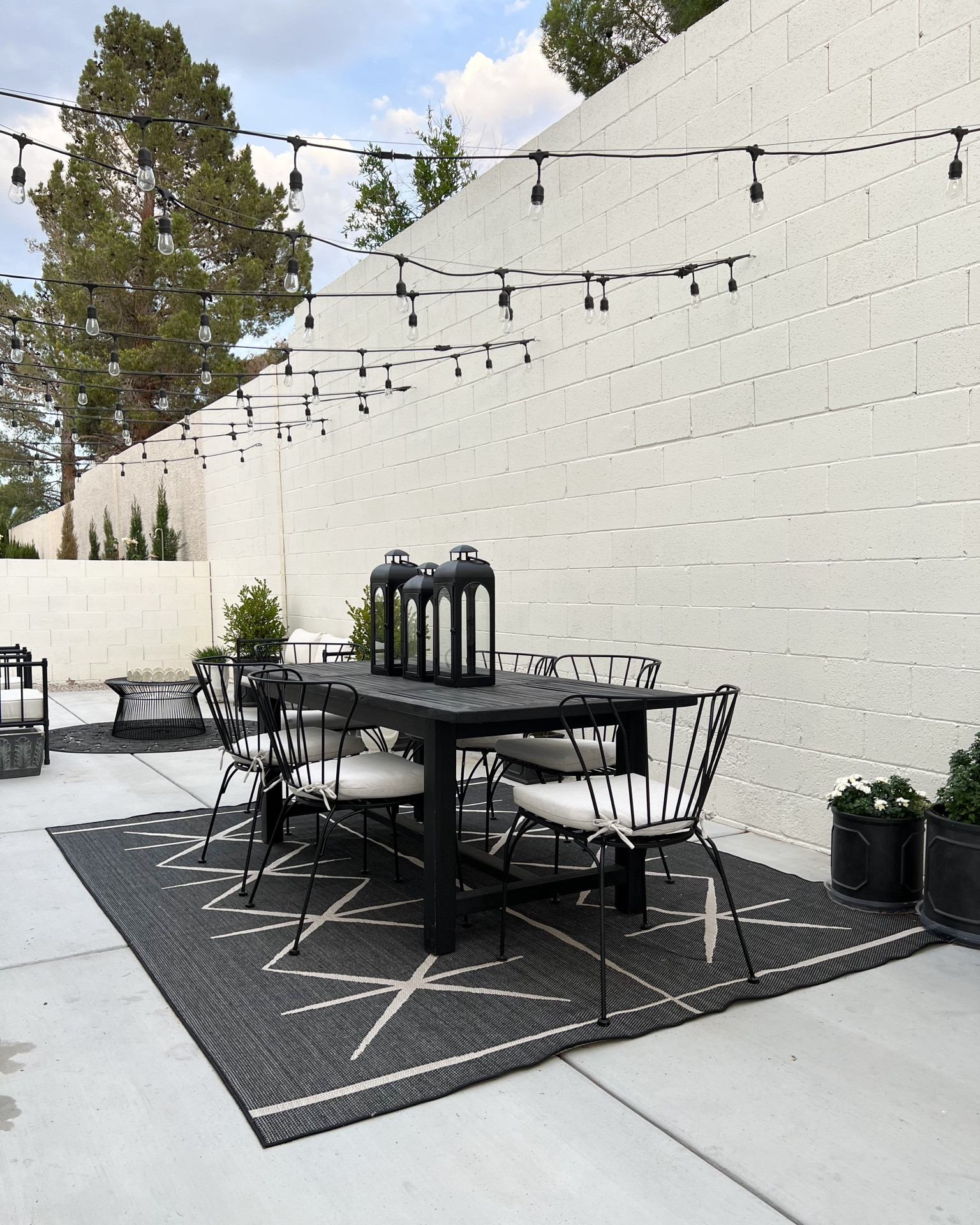 Outdoor living. Outdoor furniture. Dining table, metal chairs, outdoor rug, lanterns, string lights, Café lights, outdoor sitting. Summer gatherings 

#LTKHome #LTKSeasonal