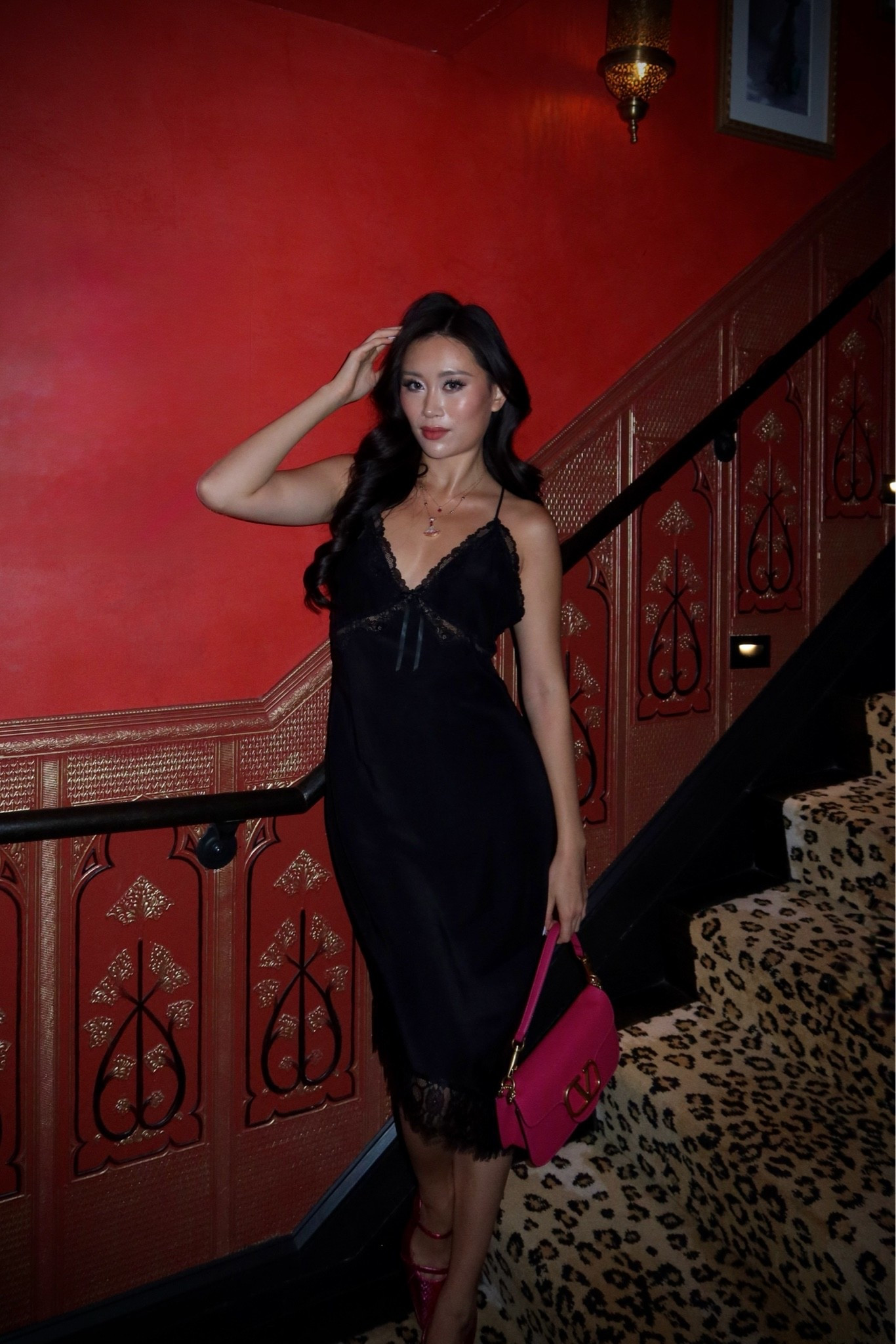 silk lace-trim slip midi dress styled with a fuchsia valentino vsling bag and hot pink strappy heels for a moody night out in a candlelit moroccan-influenced lounge in nyc. the lingerie-inspired silk silhouette and bold pink color pop create that vampy dark feminine date night moment. perfect for nyc speakeasies, italian restaurant dinners, candlelit cocktail bars, and downtown date nights. shop this look linked above.