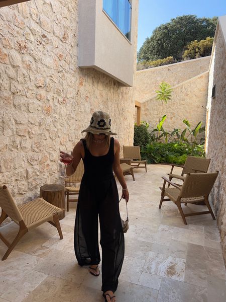 All black holiday style wearing nasty gal mesh trousers over hunza g square neck swimsuit and (primark) flower straw bucket hat - perfect minimal summer holiday style 

#LTKtravel #LTKSeasonal #LTKunder50