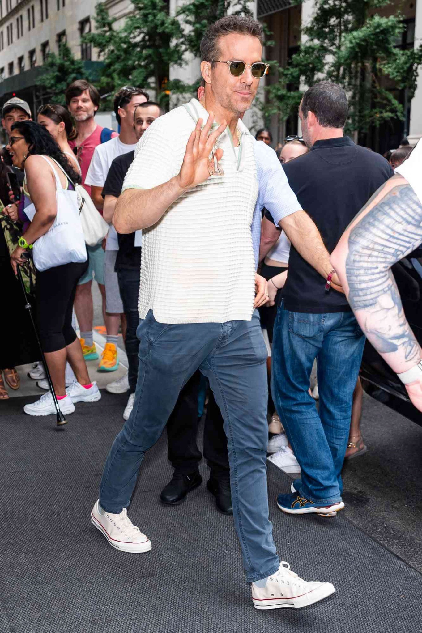 Ryan Reynolds arrives for a press junket for Deadpool & Wolverine in NYC wearing sunglasses with green lenses, a waffle-knit polo shirt, tapered chino jeans, and low top converse shoes  