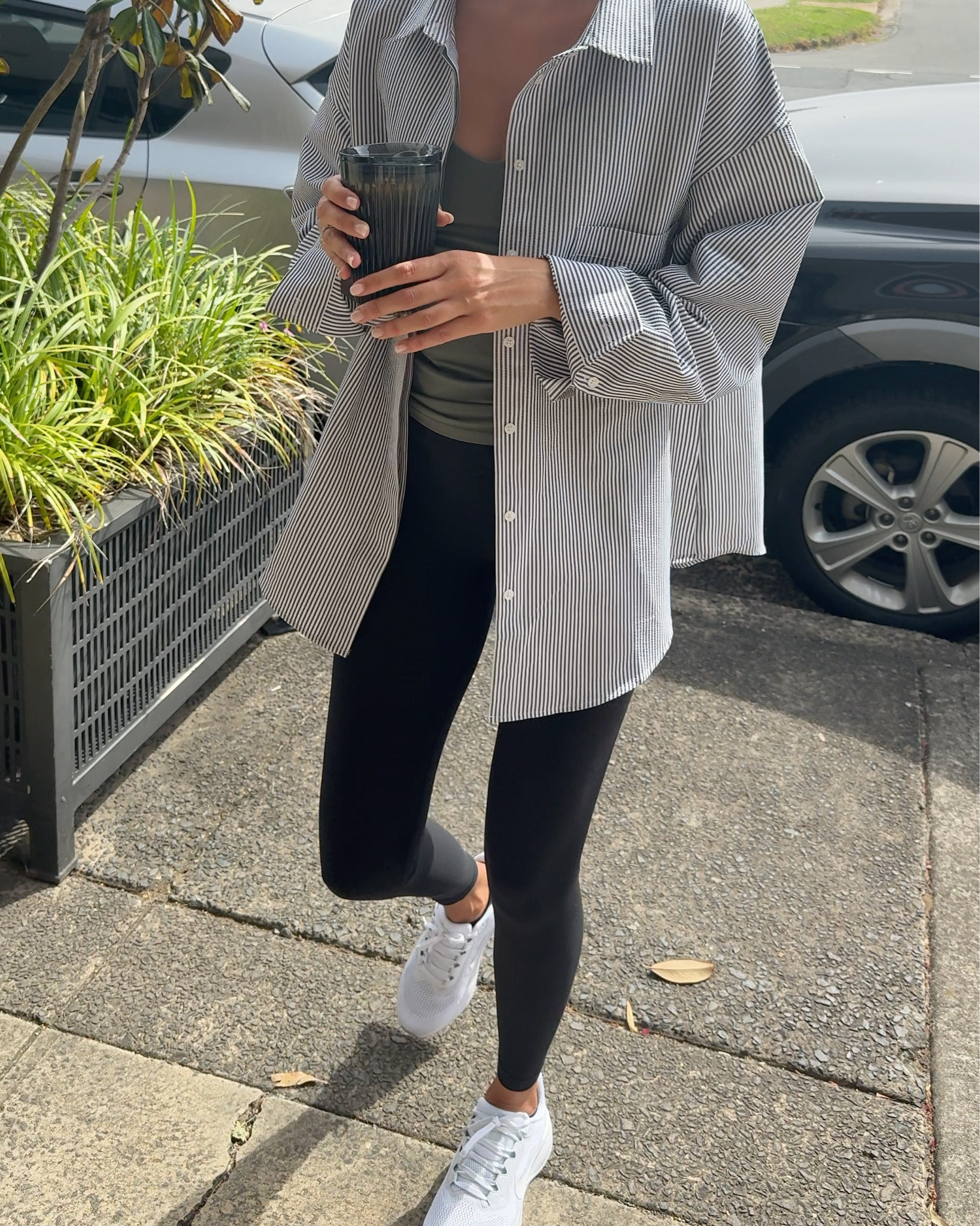 Activewear outfit featuring black Lululemon align leggings, olive green cami and and a green striped oversized shirt from Nimble. Paired with white Nike Pegasus and Miu Miu sunglasses.