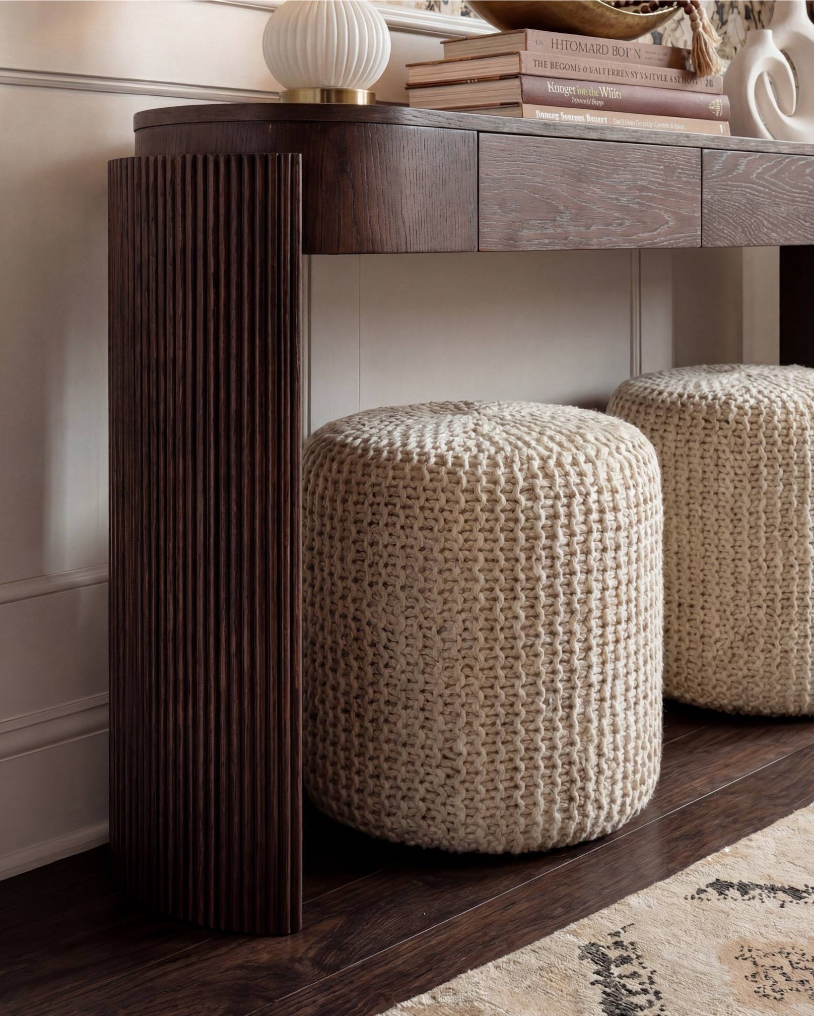 This foyer is giving warm, collected luxury, so here are the pieces that make it feel so elevated. The painterly floral wallpaper sets the entire tone, soft creams, warm taupes, and charcoal florals that instantly make the entry feel designed.

I paired it with this dark wood console (love the curved edge + ribbed detail) and styled chunky knit ottomans underneath for that cozy, layered texture. The brass globe sconces add a soft, flattering glow, and the sculptural white lamp ties everything together with its modern shape.

For styling, I kept it simple: a gold decorative bowl, a sculptural vase with greenery, and a stack of design books for height and balance. The neutral patterned runner grounds the space without competing with the wallpaper.

Shop the Look:
• Dark wood console
• Chunky knit ottomans
• Brass globe sconces
• Sculptural white lamp
• Floral wallpaper (cream/taupe/charcoal)
• Neutral geometric runner
• Gold bowl + white sculptural vase
• Design book stack

#LTKsale #LTKhome #LTKstyletip