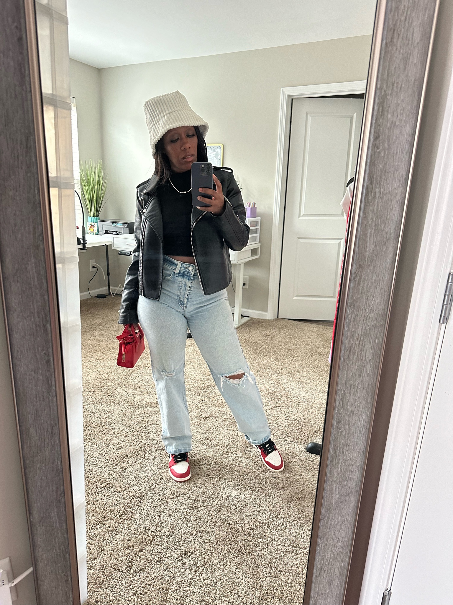 Casual sneaker outfit. Black faux leather jacket, black shirt, distressed jeans, beige bucket hat, red crossbody purse, and Jordan 1

#LTKFindsUnder100 #LTKStyleTip #LTKSeasonal