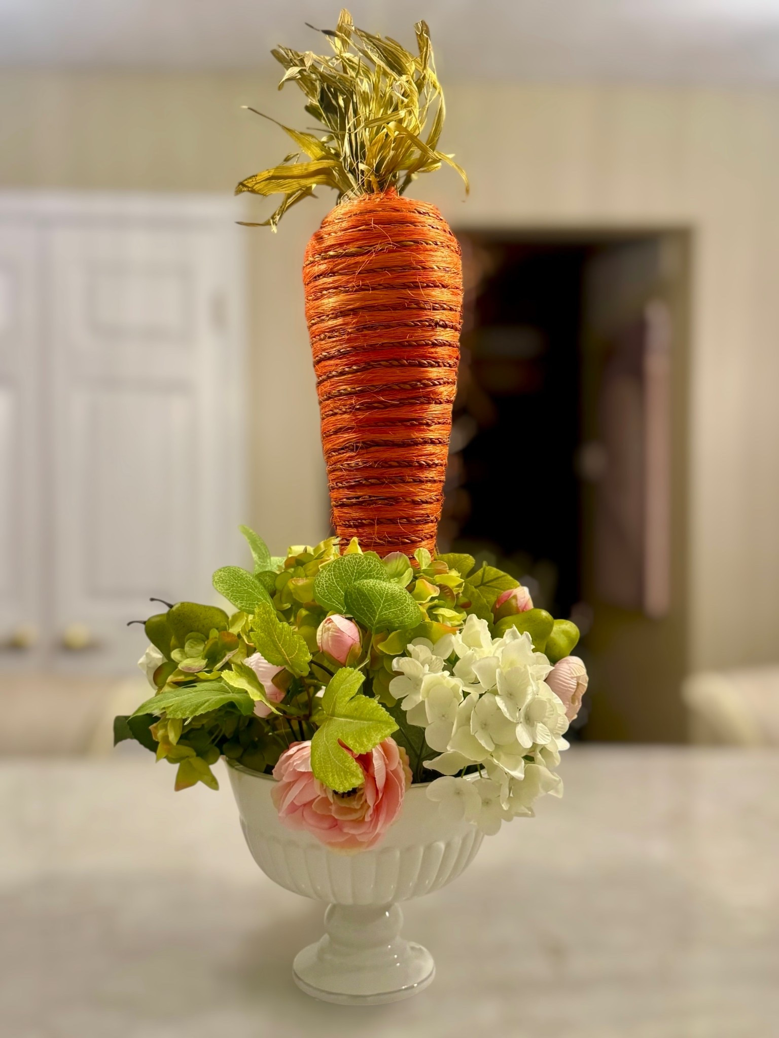 A fresh take on spring styling 🌿🥕

This elevated centerpiece blends soft, romantic florals with a playful seasonal twist. Featuring lush hydrangeas, delicate ranunculus, and layered greenery in a classic white compote—topped with a statement carrot for that unexpected, designer-inspired touch.

Perfect for Easter brunch, spring entertaining, or adding a curated moment to your kitchen or dining table. Effortless, elegant, and just the right amount of whimsy.

Shop similar florals, compote bowls, and styling pieces here 💕

#LTKhome #LTKspring #LTKseasonal #EasterDecor #SpringCenterpiece #TablescapeStyle #HomeDecorInspo #NeutralDecor #EntertainingAtHome #FloralDecor