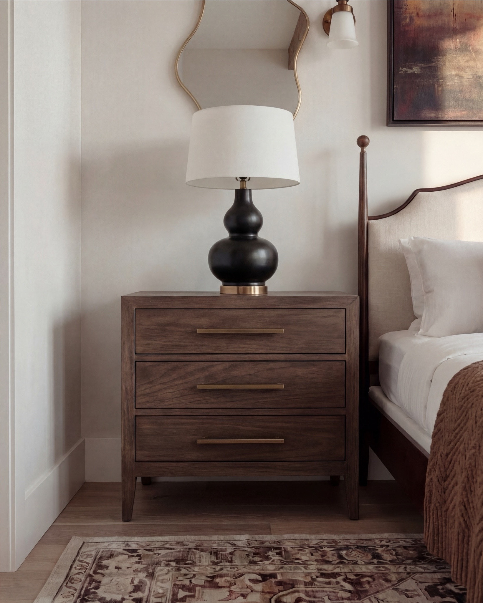 Shop the Look: Bedroom Refresh
• Dark wood bed frame with curved headboard
• Crisp white bedding set (duvet + sheets)
• Warm brown accent pillows
• Textured knit or woven throw blanket (camel/brown)
• Ivory boucle bench stools (set of two)
• Vintage-style patterned area rug (neutral brown + taupe tones)
• Wood nightstands with drawers
• Table lamps with white drum shades
• Wall sconces with brass detail
• Framed landscape artwork above bed
• Organic-shaped wall mirrors (brass frame)
• Black fluted dresser with brass hardware
• Round brass wall mirror
• Sculptural white ceramic bowl
• Decorative books with wood bead garland
• Neutral ceramic vase with dried branches
• Upholstered accent chair (cream fabric, wood frame)
• Slim brass floor lamp with white shade

#LTKhome #LTKsale #LTKstyletip