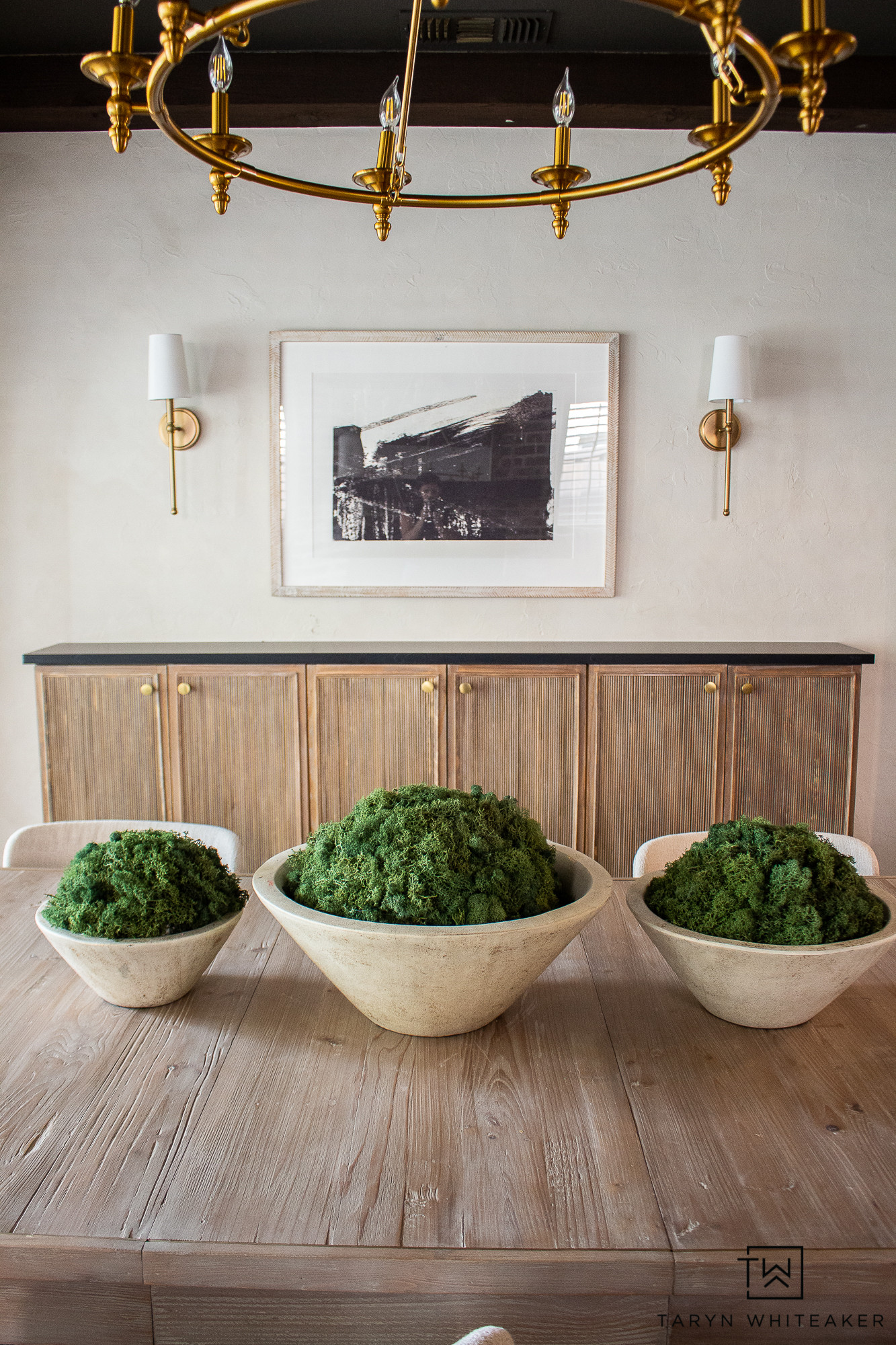 This dining room setup is all about warm tones and simple, layered texture. Neutral bowls with soft greenery add just enough contrast to the wood table without feeling busy, and the brass lighting brings in that classic, elevated touch. A reminder that sometimes less really is more when it comes to styling a space.

#LTKHome #LTKmomlife #LTKSeasonal
