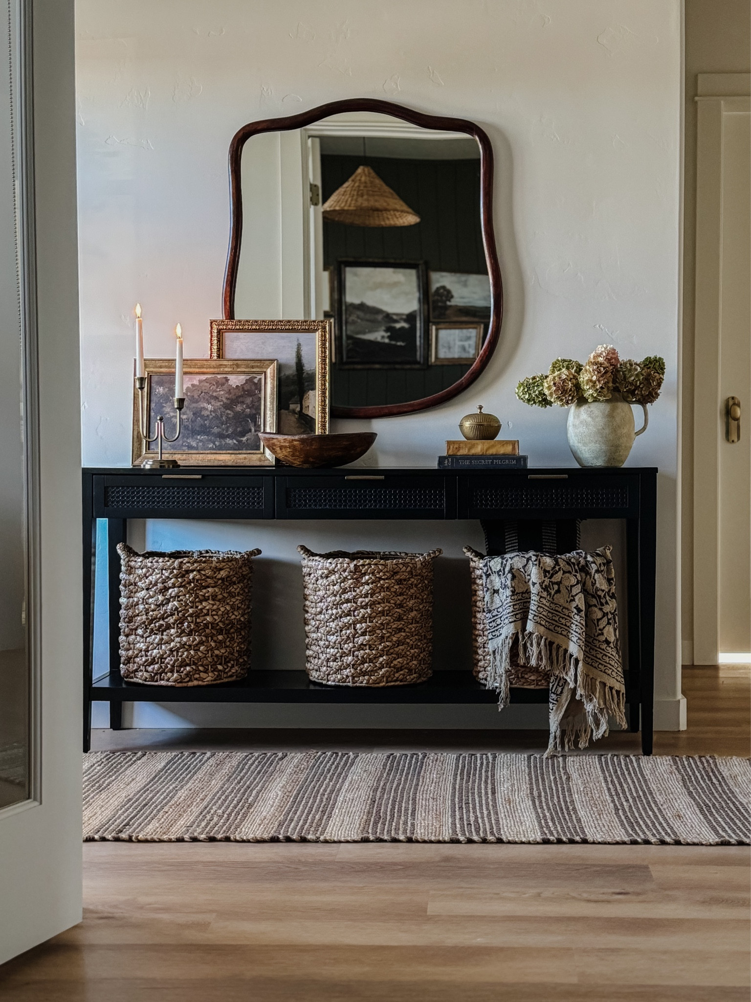 Entryway inspiration, console table styling, home decor, transitional style, organic modern, black console table, paper mache bowl, brass candlesticks, large wicker basket, vintage throw, rattan conical lamp shade, antique inspired large mirror, minka pot, modern mirror, large mirror, Loloi rug, transitional design, low pile rug, wall art, collected look
 

#LTKhome #LTKstyletip #LTKsalealert