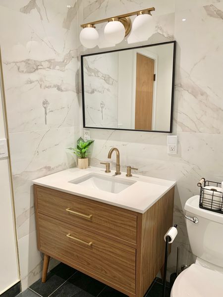 Bathroom is almost complete!  In staying with the neutral and black mid-century modern style, we used a black mirror, gold brass vanity light, a walnut wood color vanity (mine is 36”). Marble like porcelain tile wall really elevates the room and covers the whole shower area too. Just need our new door hung.  Vanity comes in multiple sizes - linked below. 

Black wire basket
Toilet paper holder
Gold faucet
Gold hardware
Toilet
Wayfair
Lowes
Pottery Barn

#LTKhome #LTKsalealert #LTKfamily