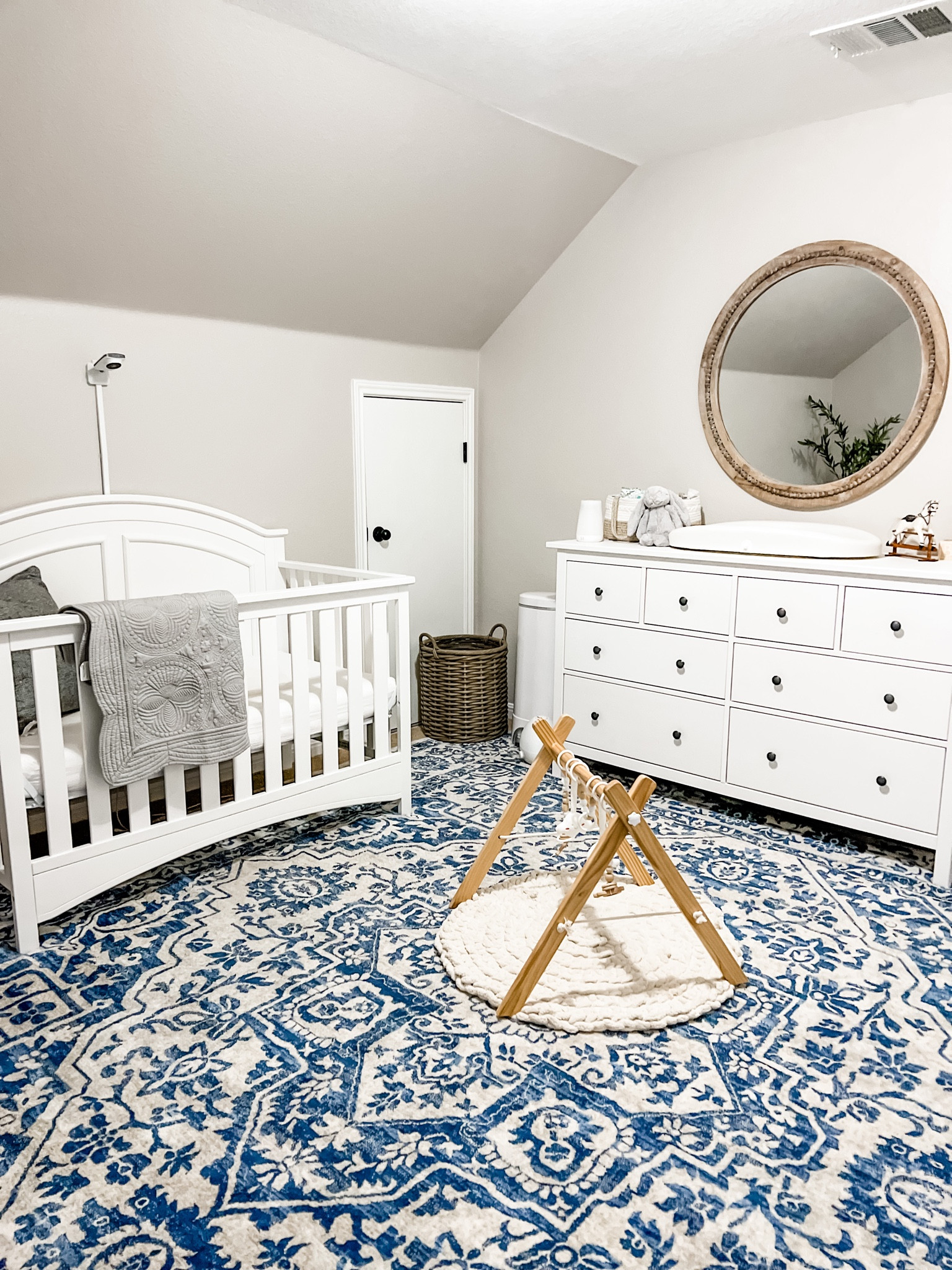 Simple baby boy nursery with blues whites and greys. 
.
White target crib, blue square rug, beautiful play gym, round hanging mirror, grey baby quilt, hatch changing pad, diaper caddy, jelly cat stuffed bunny. 

#LTKhome #LTKbaby #LTKbump