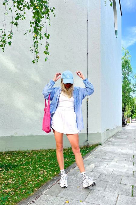 Summer Weekend Look. Fashion Blogger Girl by Style Blog Heartfelt Hunt. Girl with blond hair wearing a baseball cap, oversized striped shirt, pink sunglasses, pink crochet bag, sweat shorts, white socks and New Balance trainers. #weekendlook #sweatshorts #stripedshirt #oversizedshirt #colorfuloutfit #colorfulstyle #colorfulfashion #colorfullooks #fashionfun #cutesummeroutfit #summerfashion2023 #summerlookbook #fitcheck #dailylooks #dailylookbook #contentcreator #microinfluencer #discoverunder20k