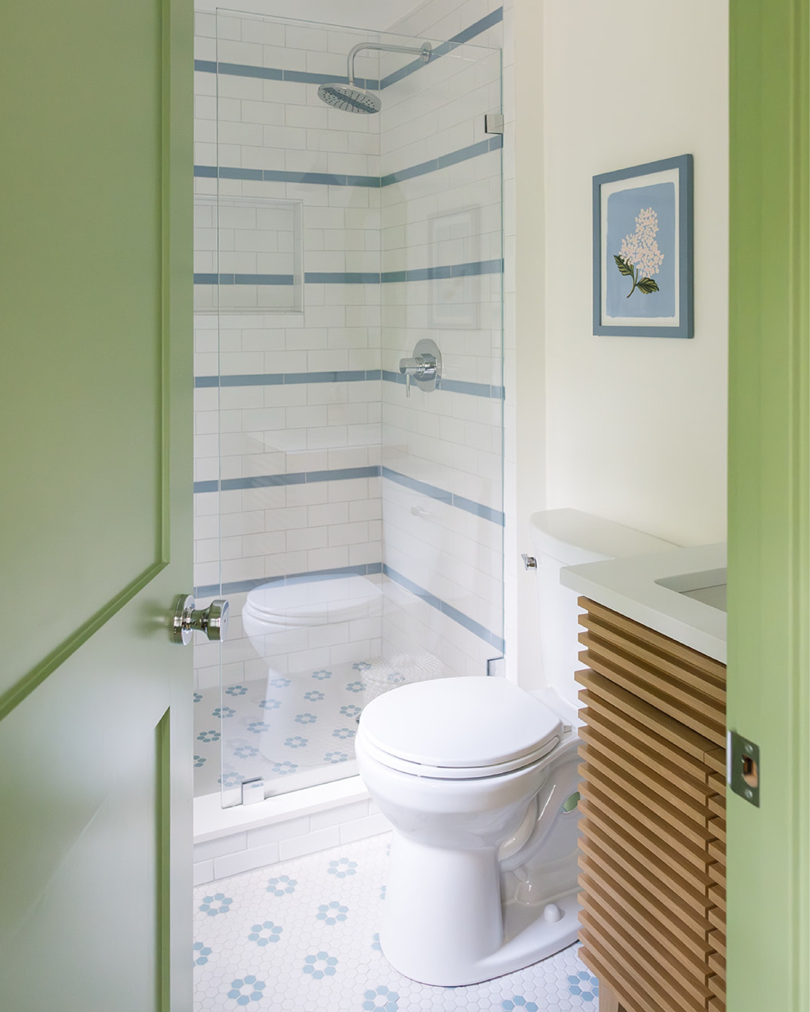 there's just something about this bathroom that gives us that squeaky clean feeling! when redesigning the primary bathroom at the #preppyhollowhouse, we knew that we wanted to convert the existing tub into a walk-in shower and incorporate blue and white striped tile. we love how the light green trim paint offers a fresh take on a classic color scheme. blue and white floral hexagon tile, a white oak vanity, blue sconce, and vintage mirror add the finishing touches to this light and airy bathroom. #dwelloctoberstay #dwelloctober

#LTKHome