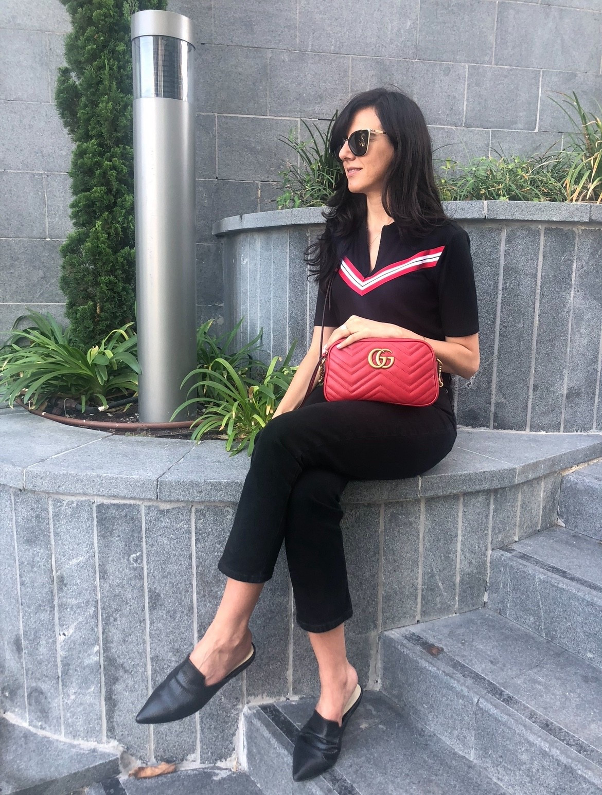Effortless chic in black and red. A sleek knit top with a bold stripe detail, cropped black pants, and pointed mules keep the look polished yet relaxed. The pop of color from the quilted red crossbody Gucci bag ties it all together. Perfect for casual city strolls or a coffee catch-up.