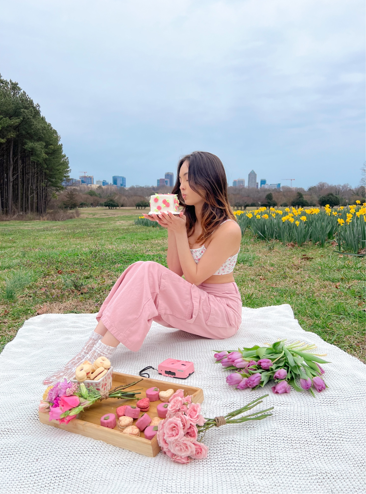 floral spring outfit pink cargo pants pink jeans pink pants spring pants floral crop top floral tank top floral cami white blanket white picnic blanket outdoor blanket picnic set wooden food tray pink Polaroid camera fake floral arrangement fake flowers lace socks