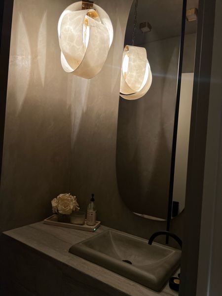 Powder room with a marble pendant, black and brass sink faucet, a concrete sink, and an oversized mirror.  

#LTKhome