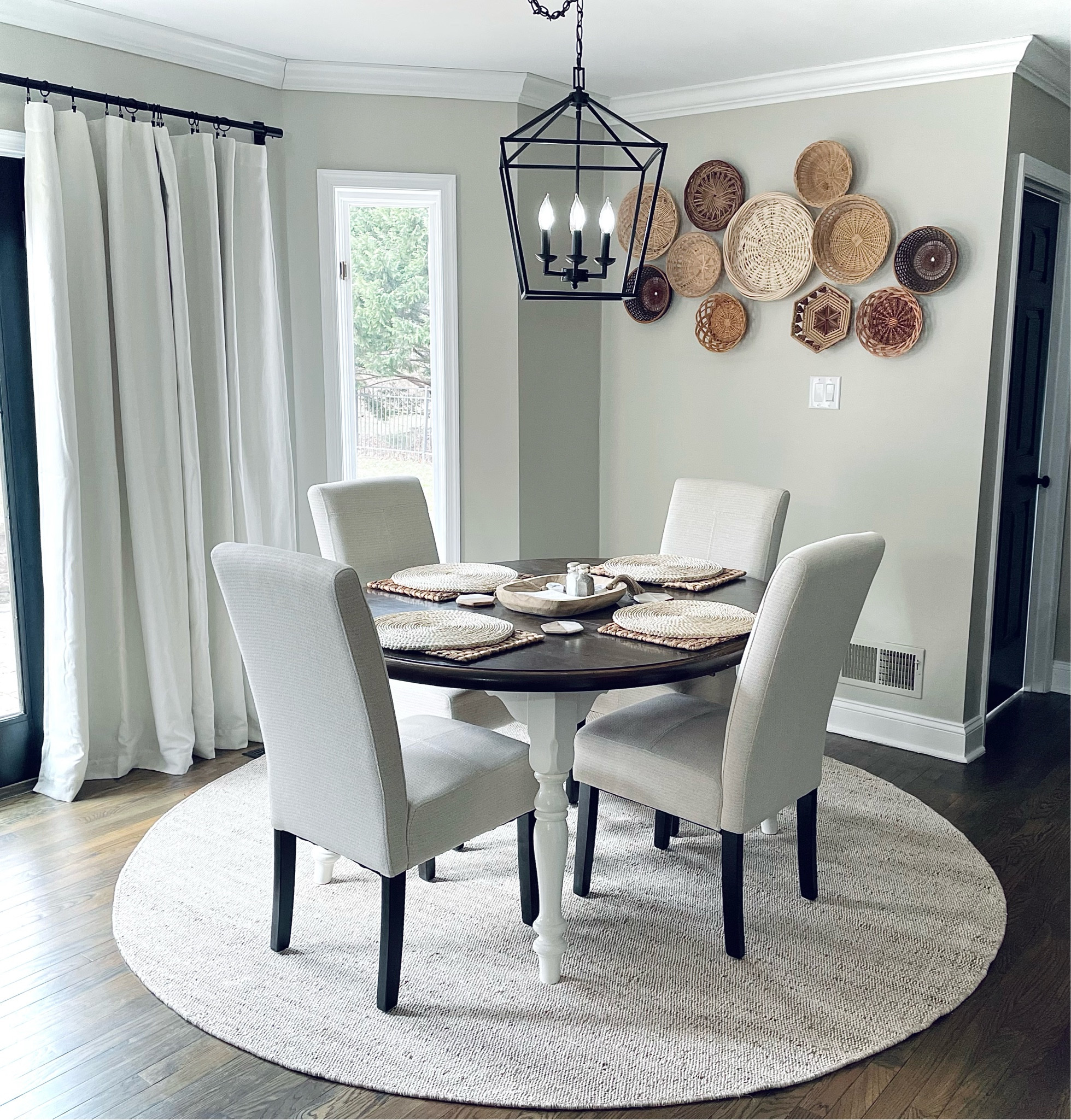 Modern farmhouse / boho breakfast nook - neutral 8’ round area rug, upholstered dining chairs, black chandelier, and curtains with added hooks

#LTKhome