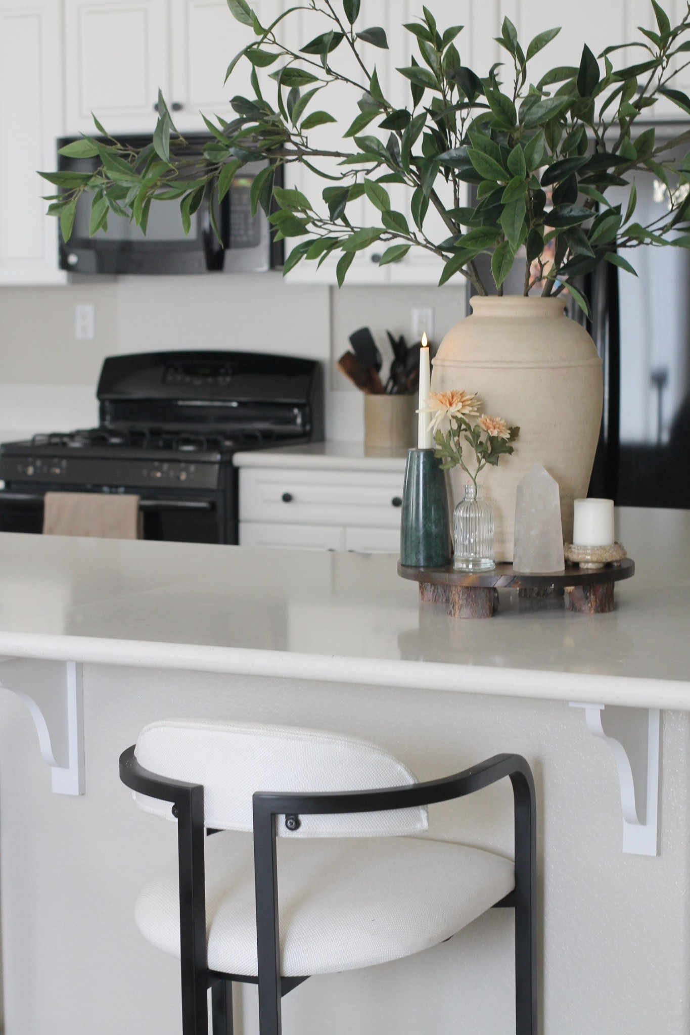 Spring kitchen island decorating
Beige vase, green stems from Pottery Barn
Orange flowers from Target
Green marble candlestick holder 
Quartz Crystal and candles
Wooden stand 
Black metal upholstered bar stools 
White kitchen 
Organic modern home decor 

#LTKHome #LTKFindsUnder50 #LTKSeasonal
