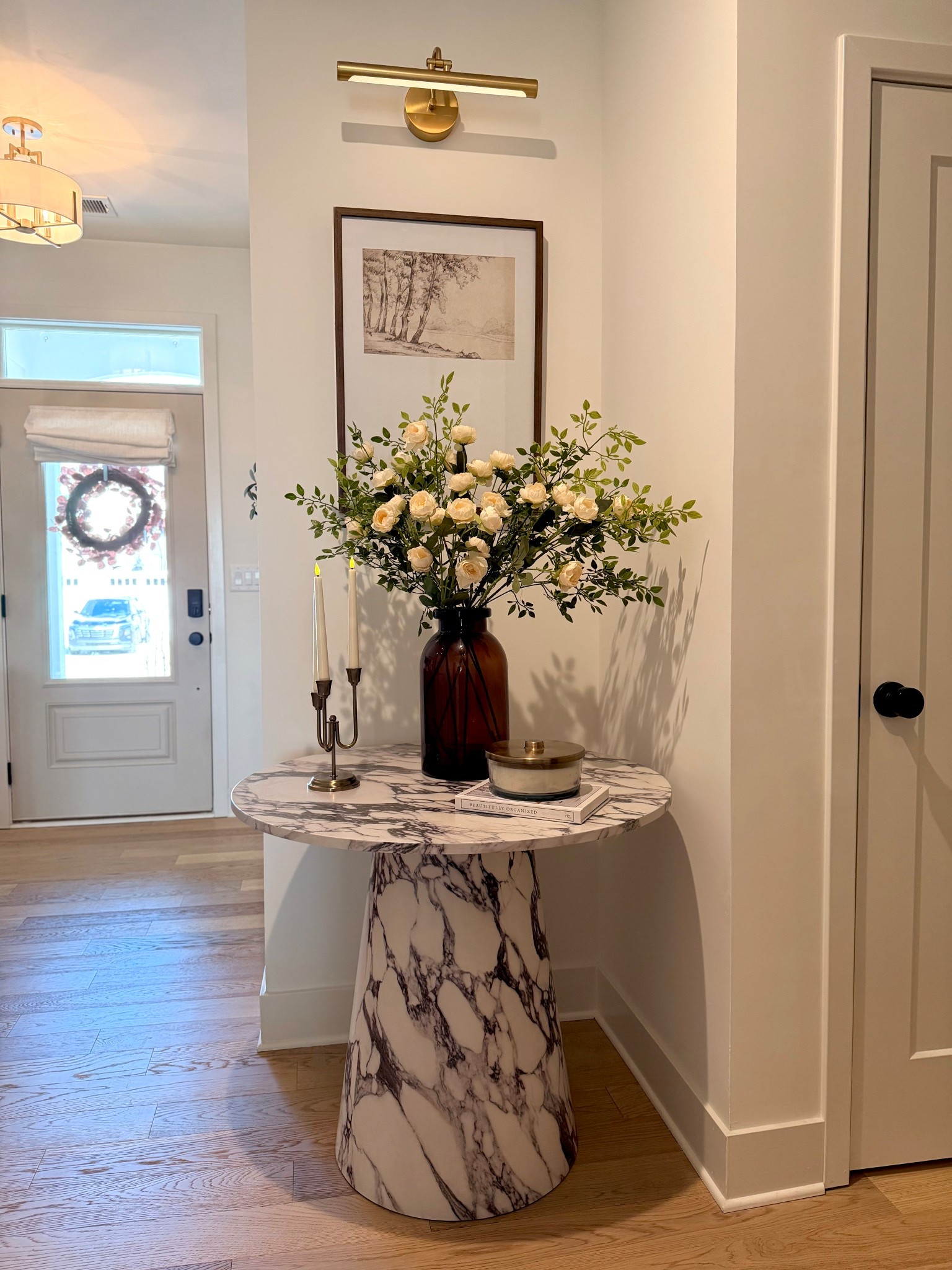 This vignette is meant to feel intentional and timeless where old-world elegance meets clean, modern lines. The marble pedestal table acts as a sculptural anchor, grounding the space with classic materiality, while the warm brass picture light and candlesticks nod to heritage details. Soft florals and vintage inspired artwork add patina and romance, keeping it from feeling too stark. Altogether, it’s a quiet moment that feels curated, layered, and effortlessly lived in true modern heritage.

#LTKHome #LTKOver40 #LTKdayinmylife
