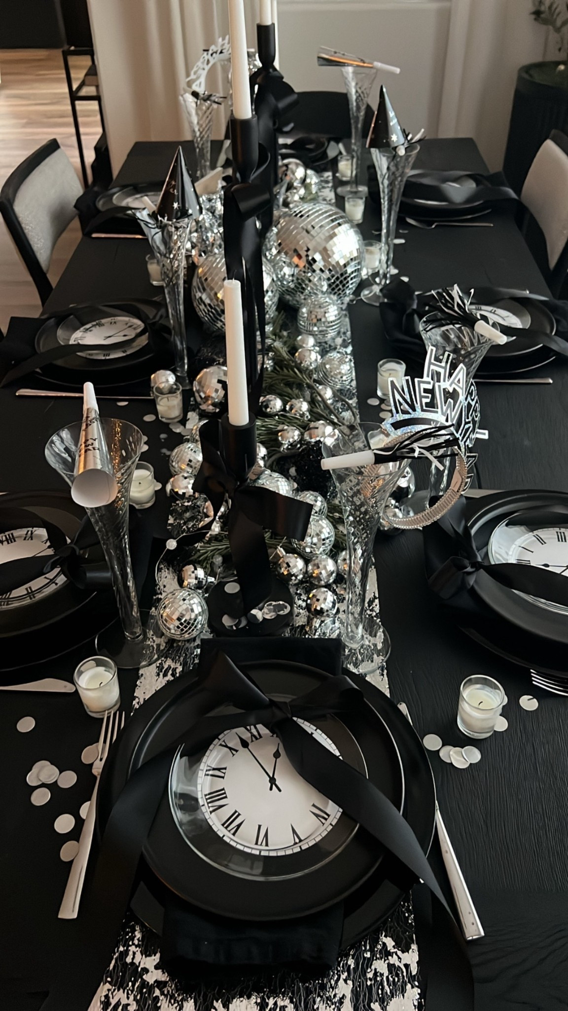 New Year’s Eve party tablescape! Dress up the table for your New Year’s party with clock faves, satin ribbon, disco balls, silver disco ornaments, New Year’s party supplies, New Year’s hats and blowers, silver runner, silver confetti