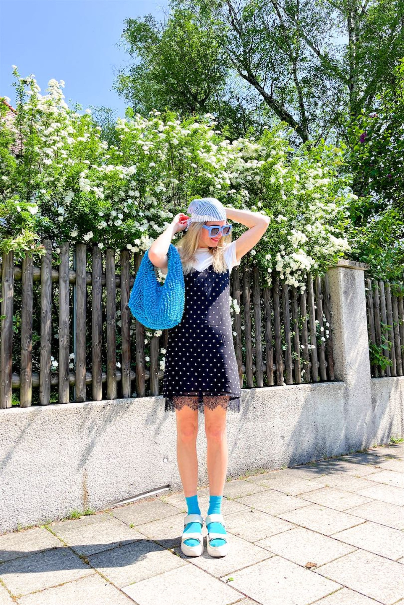 Polka Dot Mix. Fashion Blogger Girl by Style Blog Heartfelt Hunt. Girl with blond hair wearing a polka dot mix look with a polka dot bandana, tee with puff sleeves, polka dot slip dress, blue oversized sunglasses, blue statement bag, blue socks and chunky sandals. #bluelook #slipdress #polkadotdress #colorfuloutfit #colorfulstyle #colorfulfashion #colorfullooks #fashionfun #cutesummeroutfit #summerfashion2023 #summerlookbook #fitcheck #dailylooks #dailylookbook #contentcreator #microinfluencer #discoverunder20k 