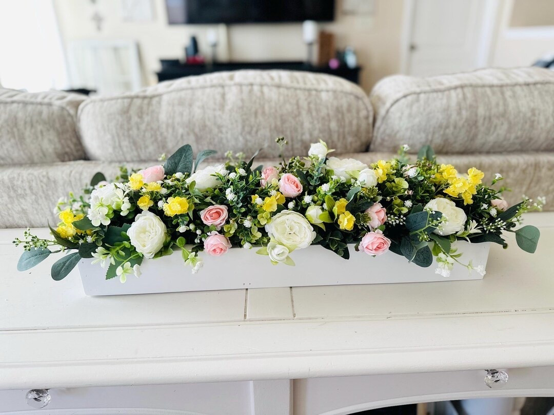 Soft, romantic, and effortlessly timeless—this handcrafted floral centerpiece brings a fresh-from-the-garden feel to your home without any maintenance. Designed with lifelike white ranunculus or peonies, blush roses, and lush greenery, it’s perfectly arranged in a beautifully made wooden planter that adds warmth and charm to any space. Whether styled on a dining table, entryway, or for a seasonal gathering, this piece blends farmhouse coziness with elegant detail for a look that lasts year-round. #LTKhome #farmhousestyle #springdecor #homedecorfinds #floraldecor #cozyhome #tabledecor #seasonalstyle

#LTKSeasonal #LTKHome #LTKWedding