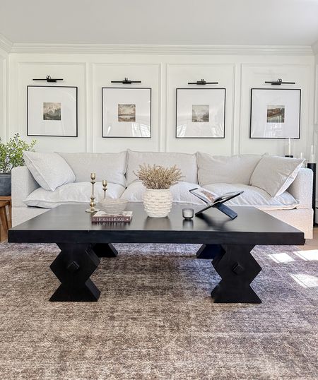 Area rug, neutral sofa, black coffee table, gallery frames 27” x 27”, rechargeable battery-operated picture lights, table decor, artificial greenery, vase, book holder, decorative bowl. 

#LTKstyletip #LTKhome #LTKsalealert