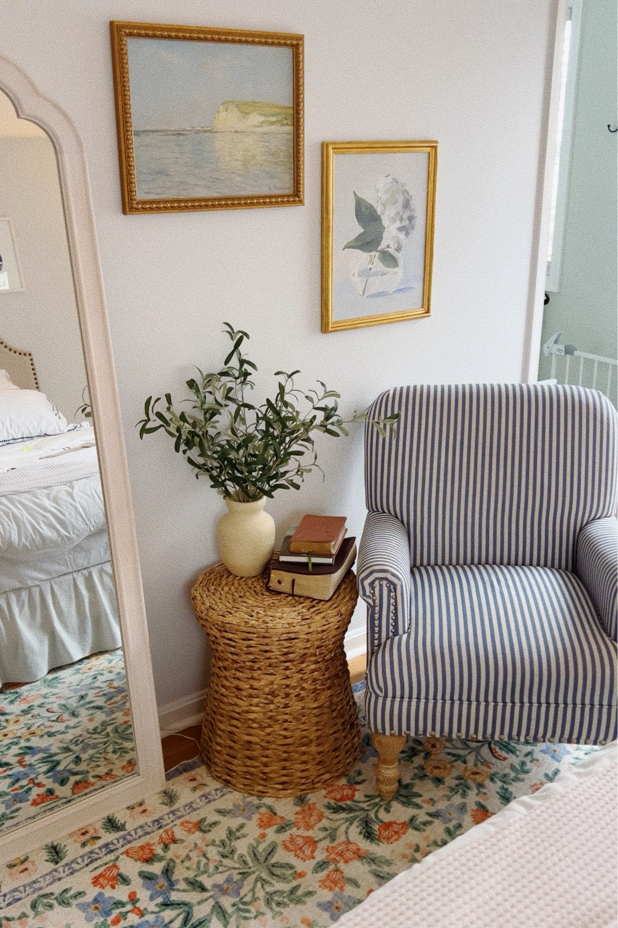 My new favorite corner in our master bedroom! 🫶🏼✨ bed and white striped chair, wicker side table, gold frame prints, faux greenery, rifle paper co rug, home decor, target finds, home refresh 

#LTKhome