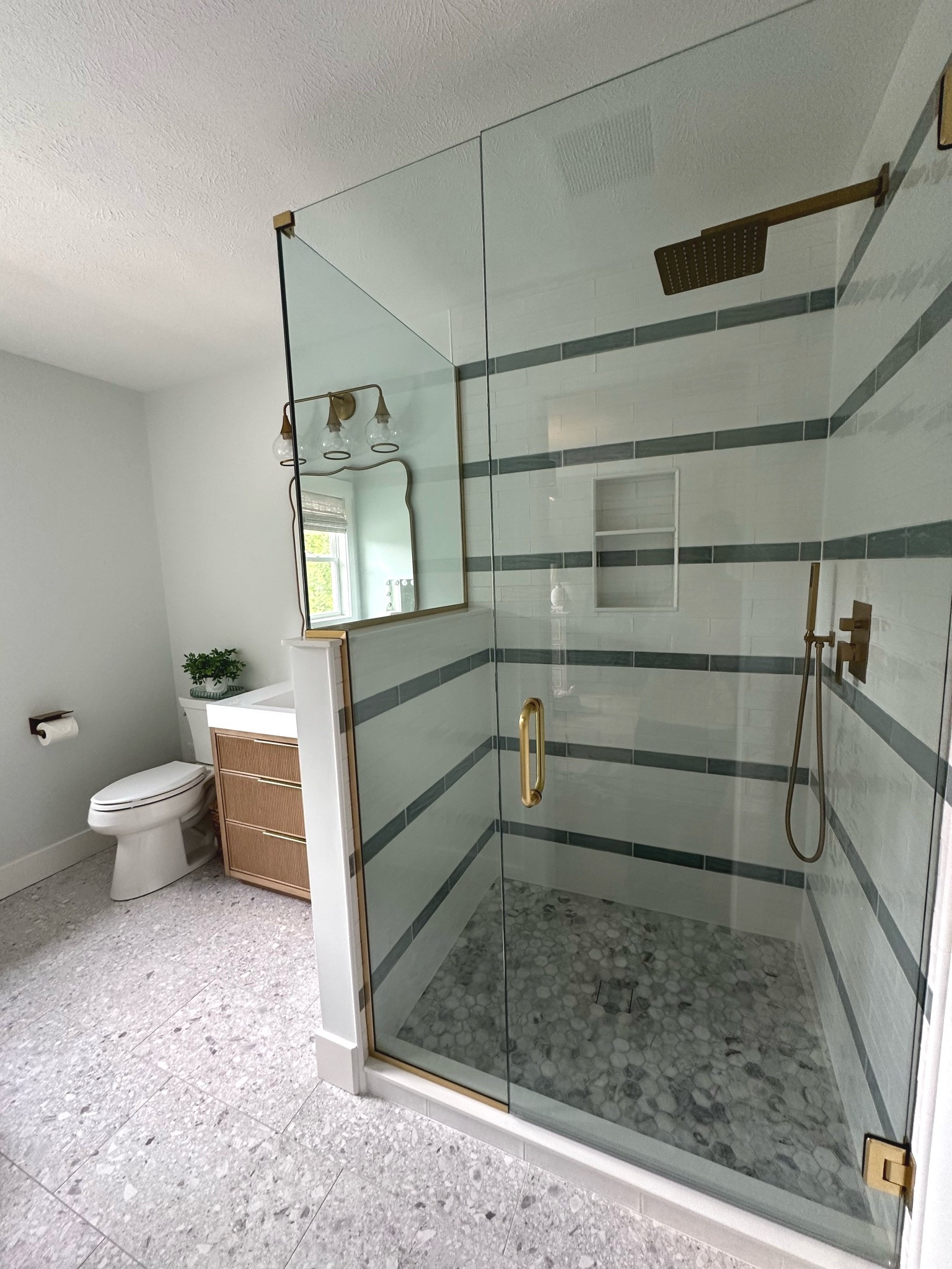 Laundry room turned teen en-suite bathroom

Shower tile: @bedrosianstile 
Floor tile: @virginiatilecompany Santiago White 12x24
Shower fixtures & vanity: @wayfair
Lighting: @shadesoflight 
Makeup vanity: @potterybarn 
Toilet: @kohler 
Wall color: Magnolia Cloudy Gray