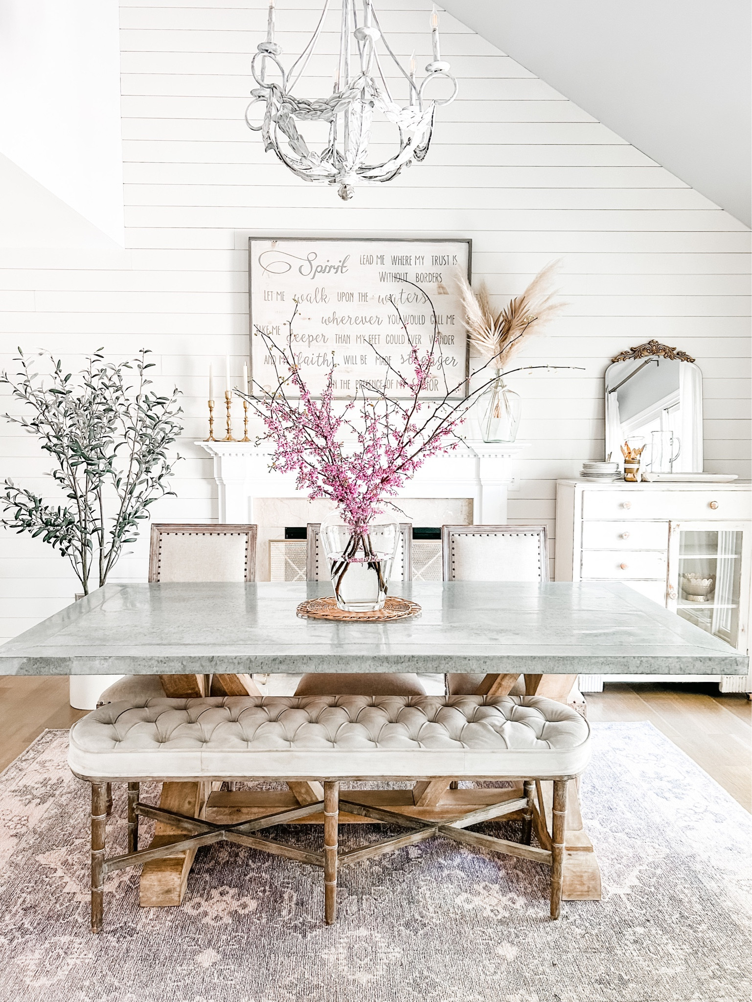Current Dining room view with red bud branches from the yard.

Dining room decor, farmhouse table, dining table, upholstered bench, artificial tree, faux tree, olive tree, gold mirror, ornate gold mirror, blush area rug, farmhouse chandelier, dining room chandelier, zinc top dining table, dining chairs with nail head trim, white farmhouse buffet, glass buffet, glass side board. Area rug, dining room rug, gold taper candle holders, gold candle holders, fire screen, fireplace screen, mantel decor. Dining room table, dining bench, large 40” pampas grass stems. 

#LTKFind #LTKhome #LTKstyletip