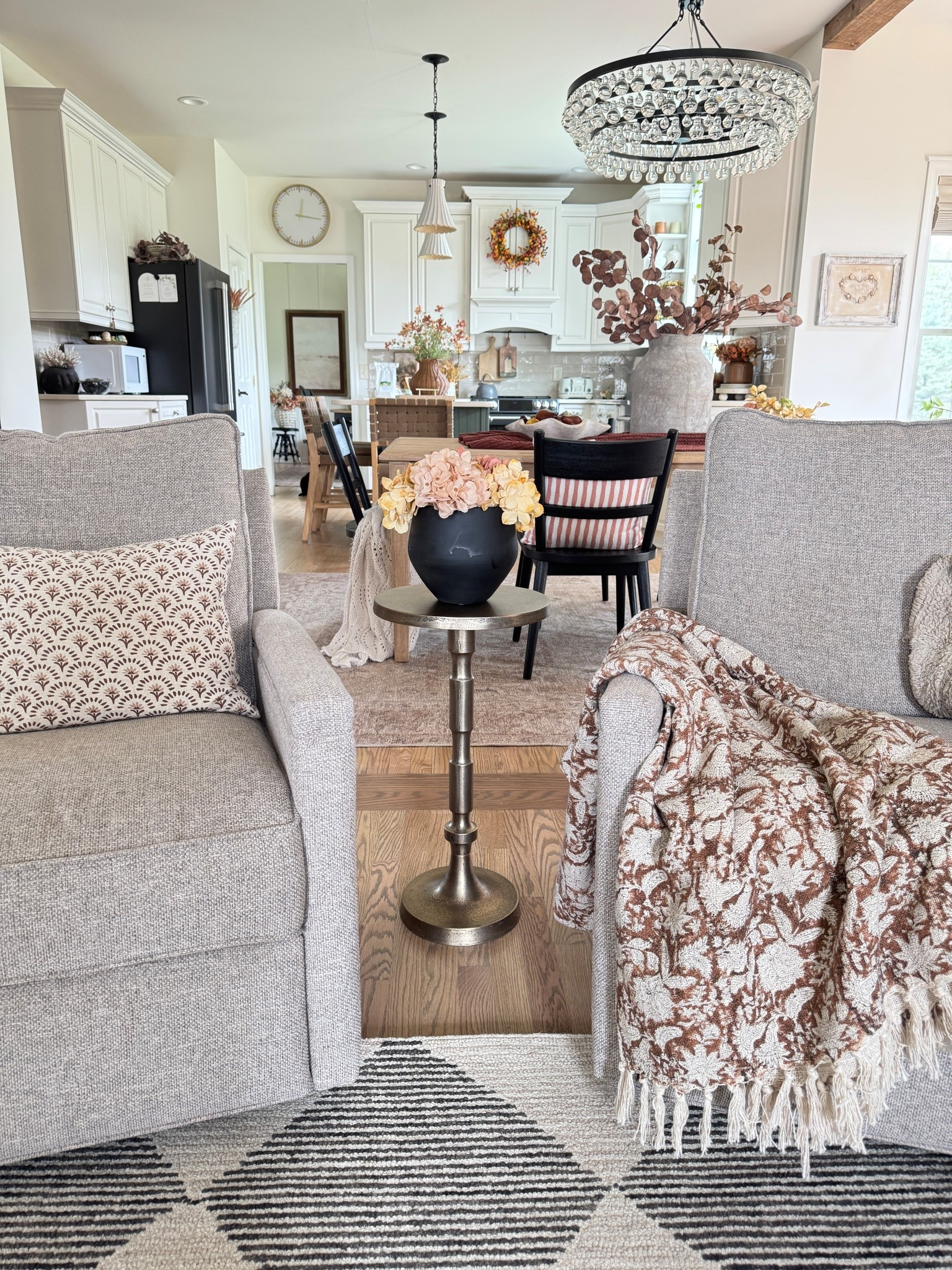 Pretty warm tones for fall. My favorite accent table in a muted gold. Looks even better in person! Some pretty hydrangea stems that I cut short to fill this black planter currently on sale. Brown and cream floral throw perfect for this time of year. Dining table and chairs. Similar ruffled bowls for faux pears and dried oranges. These two swivel recliners are the perfect accent chairs that have lower backs and are on a smaller scale but are very comfortable to sit in. Fall wreath on cabinet brings warmth to a creamy white kitchen. 

#LTKHome #LTKSeasonal #LTKSaleAlert