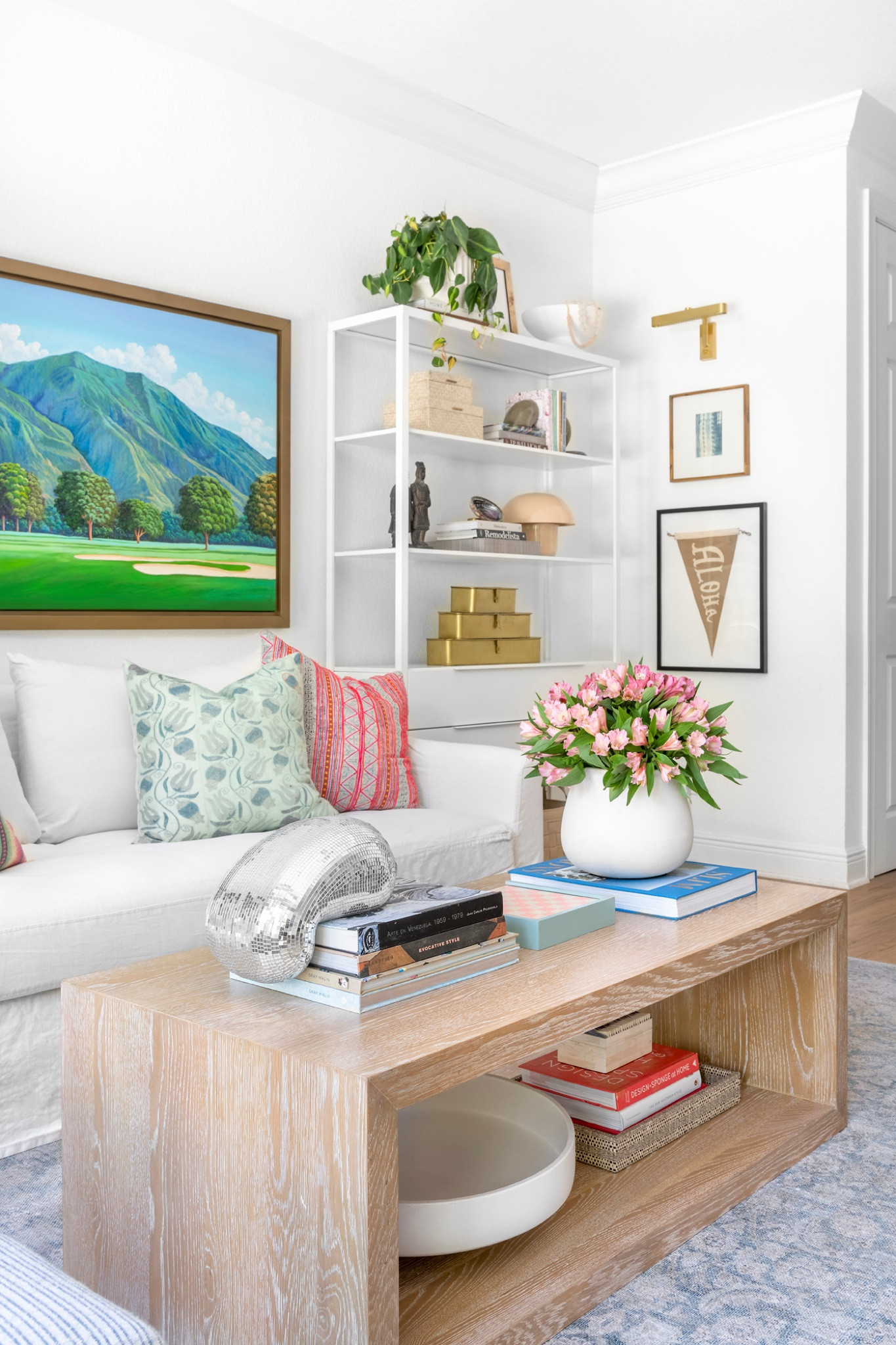 This West Palm Beach living space combines colorful, relaxed decor with personal touches for a welcoming, cozy vibe. A white sofa with textured throw pillows and a custom oil landscape painting from Caracas add warmth and meaning, while natural elements like woven baskets and plants enhance the laid-back aesthetic. Perfect for a vibrant yet serene gathering spot. 

#LTKHome
