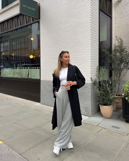 Simple autumn style wearing grey tailored wide leg trousers with white cropped tee and black trench coat 