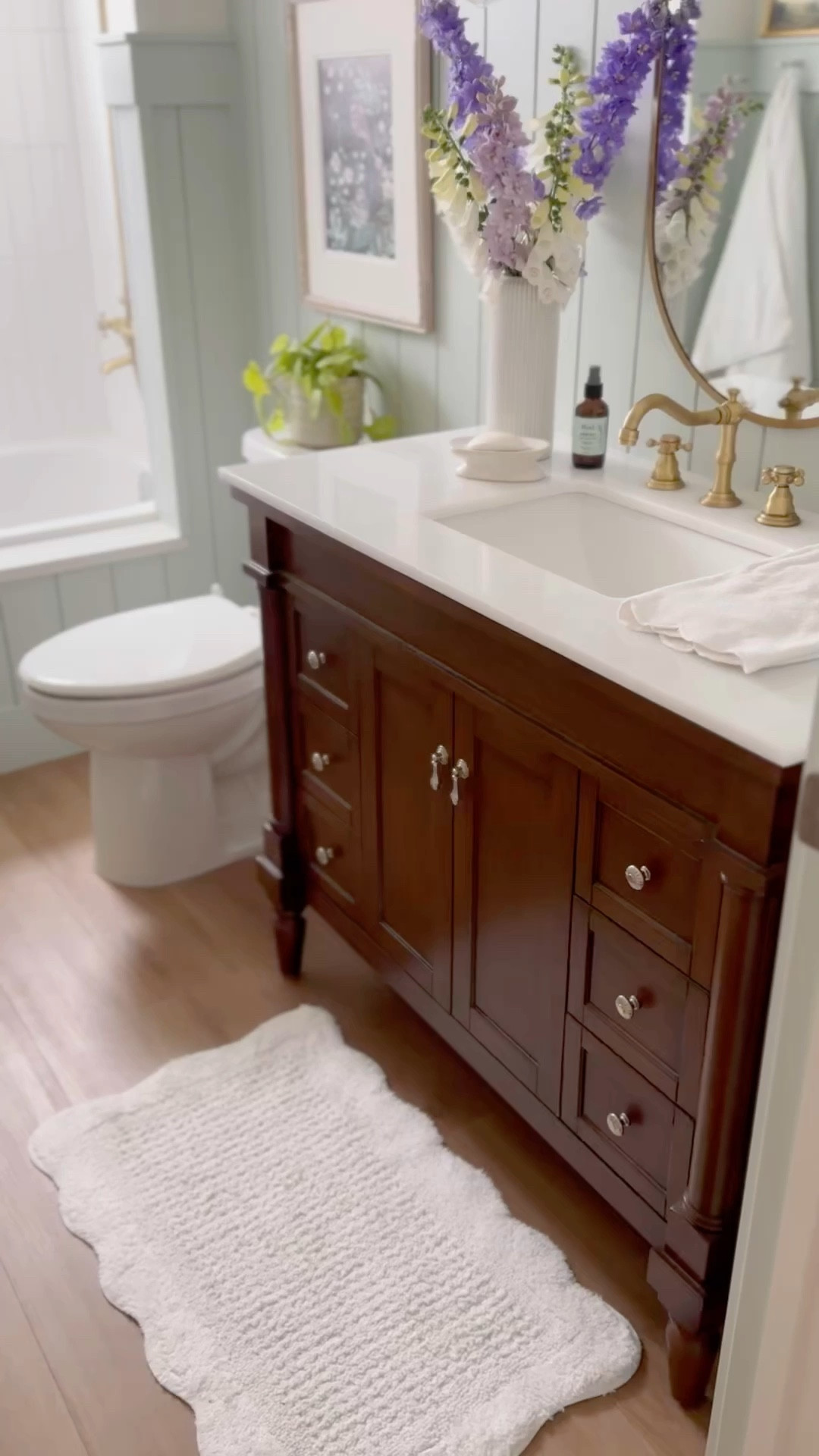 Cozy cottage vibe bathroom, traditional walnut vanity with marble top, arched drop in tub, gold faucet, gold shower fixture, flower sconces 


#LTKHome #LTKVideo #LTKSaleAlert