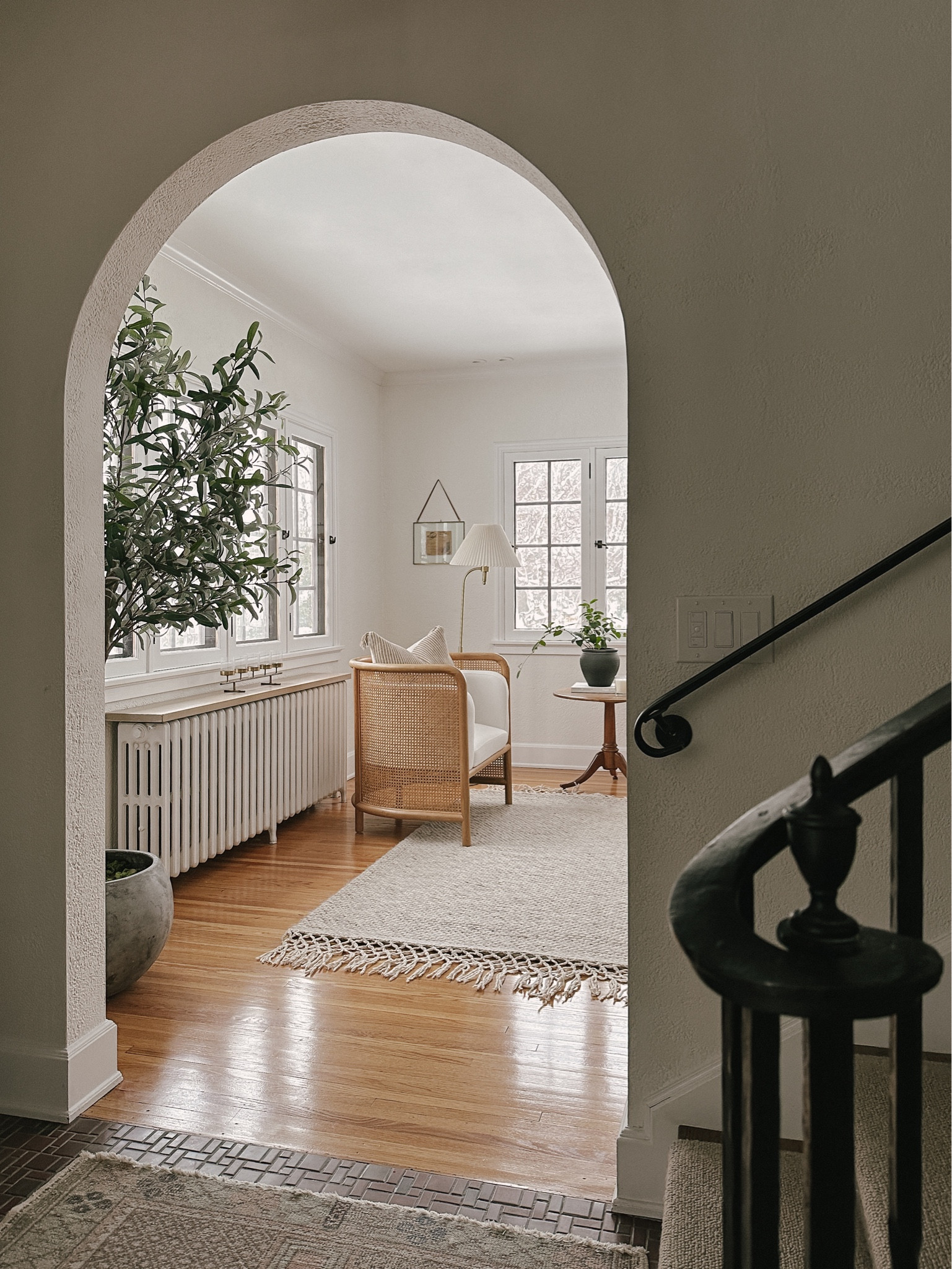 our sitting area of the living room. cane chair, wool rug, faux plant, pedestal table, black vase, floor lamp  

#LTKhome