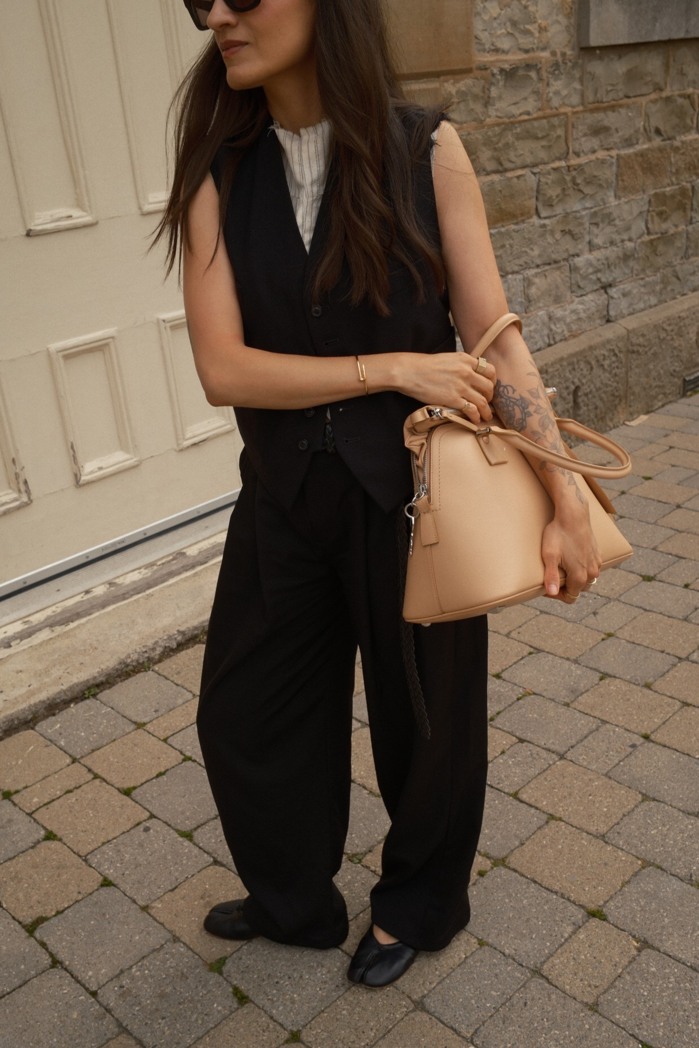 A deconstructed vest styled with black trousers, tabi ballet flats and a 5AC bag from Maison Margiela. 