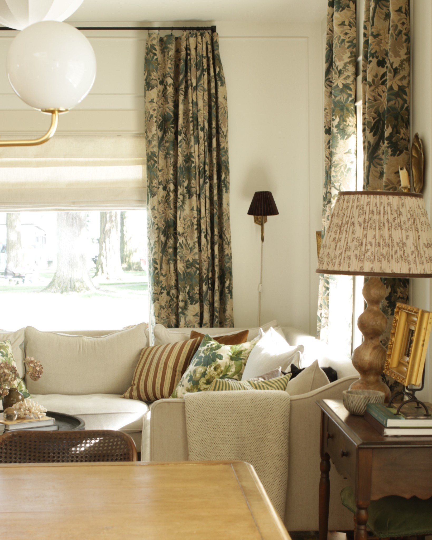 Living rooms cottage living room, tapestry, tapestry curtains, corner sectional, cream sectional, jute rug, patterned lampshade, Michael S Smith, designer pillows, curved wall sconce, rejuvenation lighting 

#LTKHome