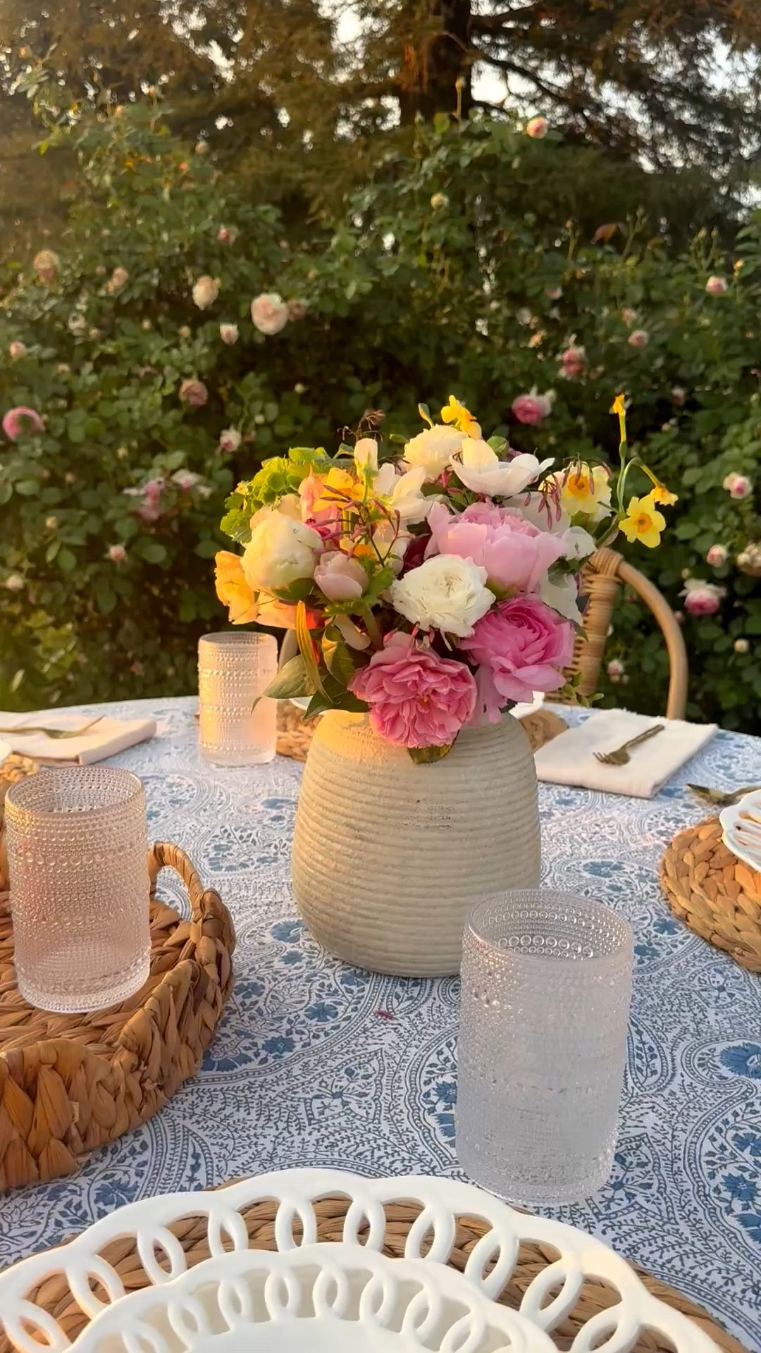 Beautiful spring brunch, lunch or dinner tablescape idea! Now that the weather is nice, we live dining al fresco in the rose garden! This beautiful pink rose in bloom is the perfect backyard backdrop! I love this blue and white block print tablecloth, this timeless ceramic vase, this scalloped rattan tray and these chic hobnail glasses!! They complement my white porcelain dinner plates beautifully! ❤️  

#LTKdayinmylife #LTKSeasonal #LTKHome