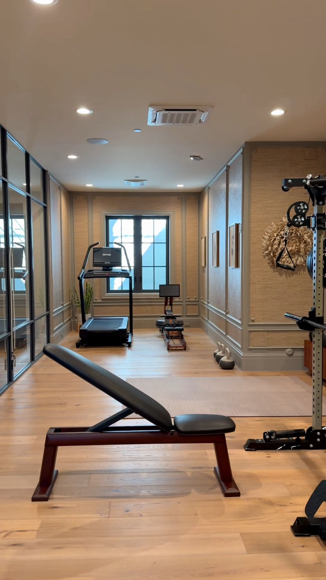 My luxe diy home gym is done! Gray paint, faux grasscloth wallpaper, wall trim with half round details, designer mats, and media tables used as weight racks! Stone sconces with tassels too.

#LTKSaleAlert #LTKHome
