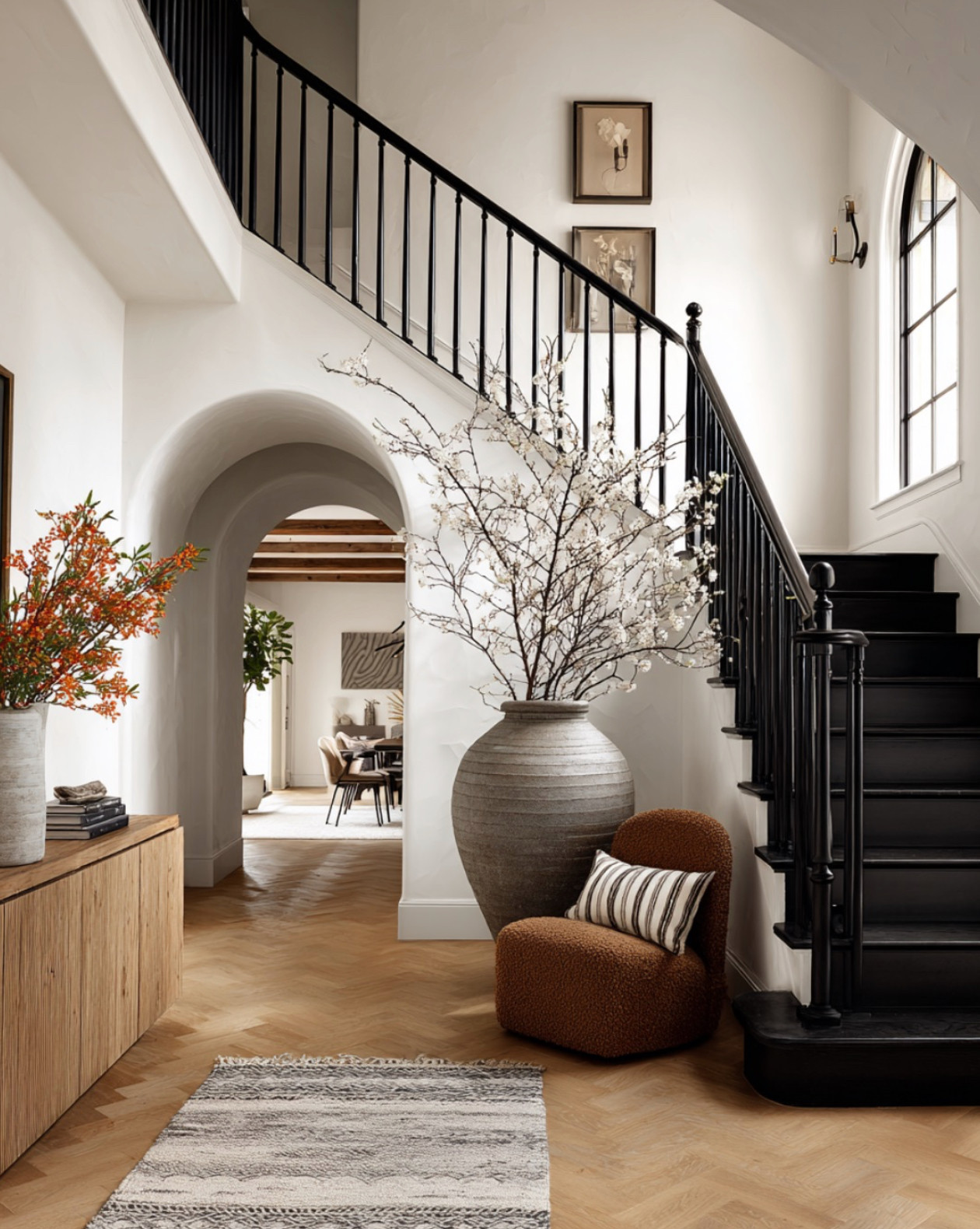 Obsessed with this warm + welcoming entryway 🤎 Loving the details in this space—from the beautiful herringbone flooring to the natural wood console table that adds the perfect touch of warmth. The boucle accent chair and striped pillow bring in cozy texture, while the layered rug grounds the whole look. And those oversized faux stems? Total statement moment. #HerringboneFlooring #ConsoleTableDecor #AccentChairStyle #TexturedThrowPillow #LayeredRugs #FauxBranches #NeutralDecorStyle #StyledEntryway #ModernEntryway #HomeDecorFinds 

 #LTKHome