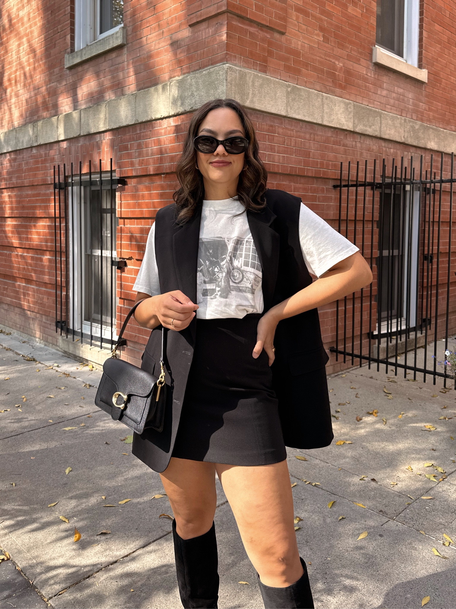 Fall outfit inspiration - details below:
-Black sleeveless blazer/vest, similar options linked. 
-Anine Bing graphic T-shirt, I am eating a leather for an oversized fit. 
-Black mini skirt from Dynamite. I have a medium  
-Black coach tabby 26 bag. 
-Celine Triomphe 52mm sunglasses in black acetate. 
-Knee a high suede black boots. 

#LTKfindsunder100 #LTKSeasonal #LTKstyletip