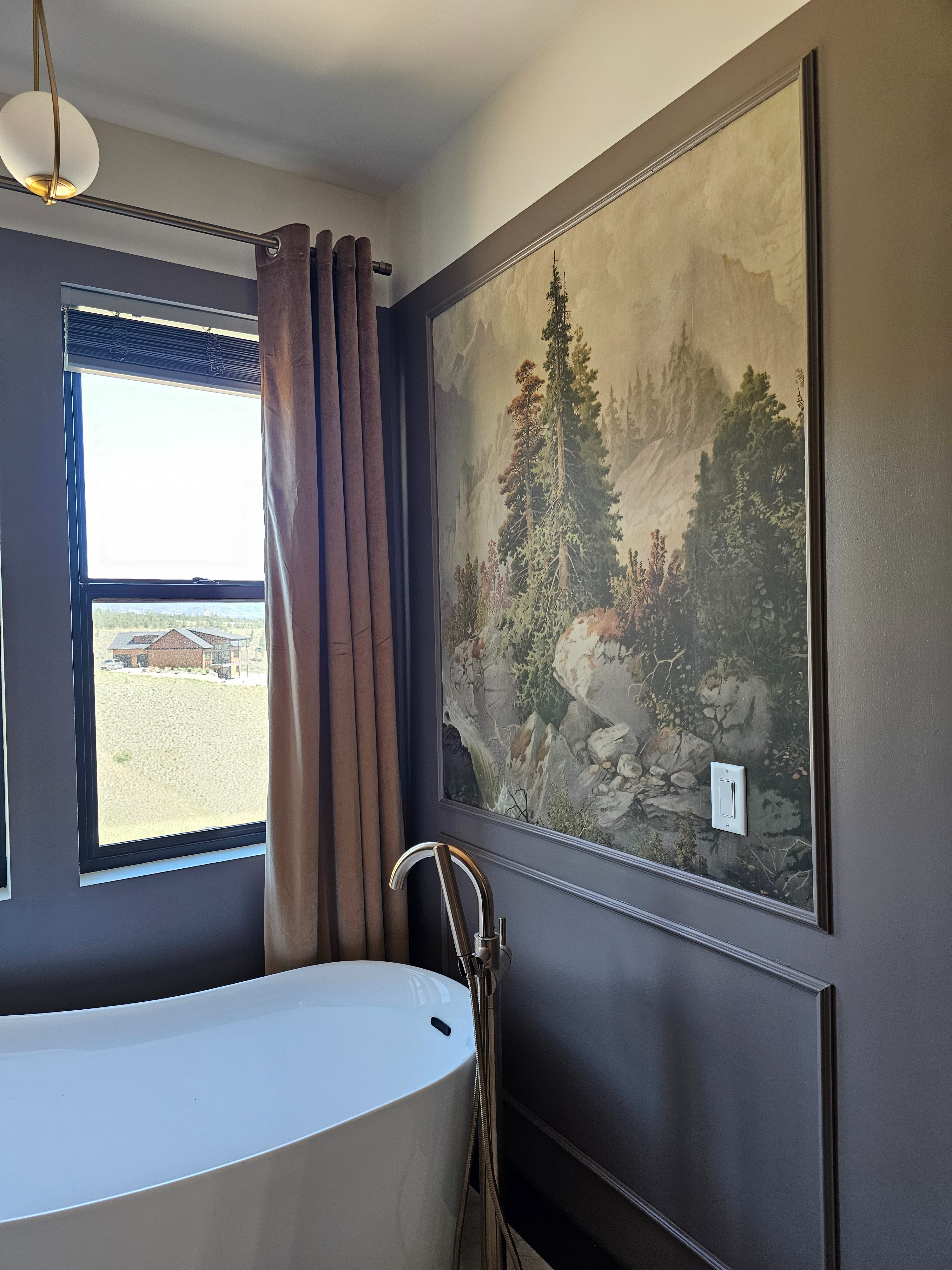 Moody Mountain Bathroom Oasis

Transform your bathroom into a luxury, nature-inspired retreat. This moody bathroom design perfectly balances modern luxury with rustic, earthy elegance. The standout feature is the breathtaking vintage forest mural wallpaper, beautifully framed by custom picture frame moulding painted in a rich, dark mushroom-taupe.

Pairing a sleek white freestanding bathtub with a high-end brushed gold floor-mount tub filler creates the ultimate spa-like focal point. Velvet grommet curtains add soft texture, while the black window frame frames the gorgeous outdoor view like a piece of living art.

Click the link in my bio to shop everything featured in this moody modern organic bathroom design! ---

Shop The Look:
Mural: Vintage Landscape Wallpaper / Forest Mural Art

Tub: Modern White Freestanding Acrylic Soaking Tub

Faucet: Brushed Brass / Gold Floor-Mount Tub Filler with Hand Shower

Drapes: Luxury Velvet Grommet Curtain Panels in Taupe/Mauve

Paint Color Vibe: Dark Mushroom, Moody Taupe, Warm Charcoal

Lighting: Modern Brass Globe Pendant Light 

 #MoodyBathroom #BathroomDesign #FreestandingTub #ModernOrganic #VintageWallpaper #MuralWallpaper #GoldPlumbing #BathroomInspo #LuxuryBathroom #SpaBathroom #PictureFrameMoulding #Wainscoting #Earthtonedesign #CozyHome #InteriorDesignInspo #BathroomRemodel #HomeDecorIdeas #WindowTreatments #VelvetCurtains #NatureInspiredHome #LTKHome