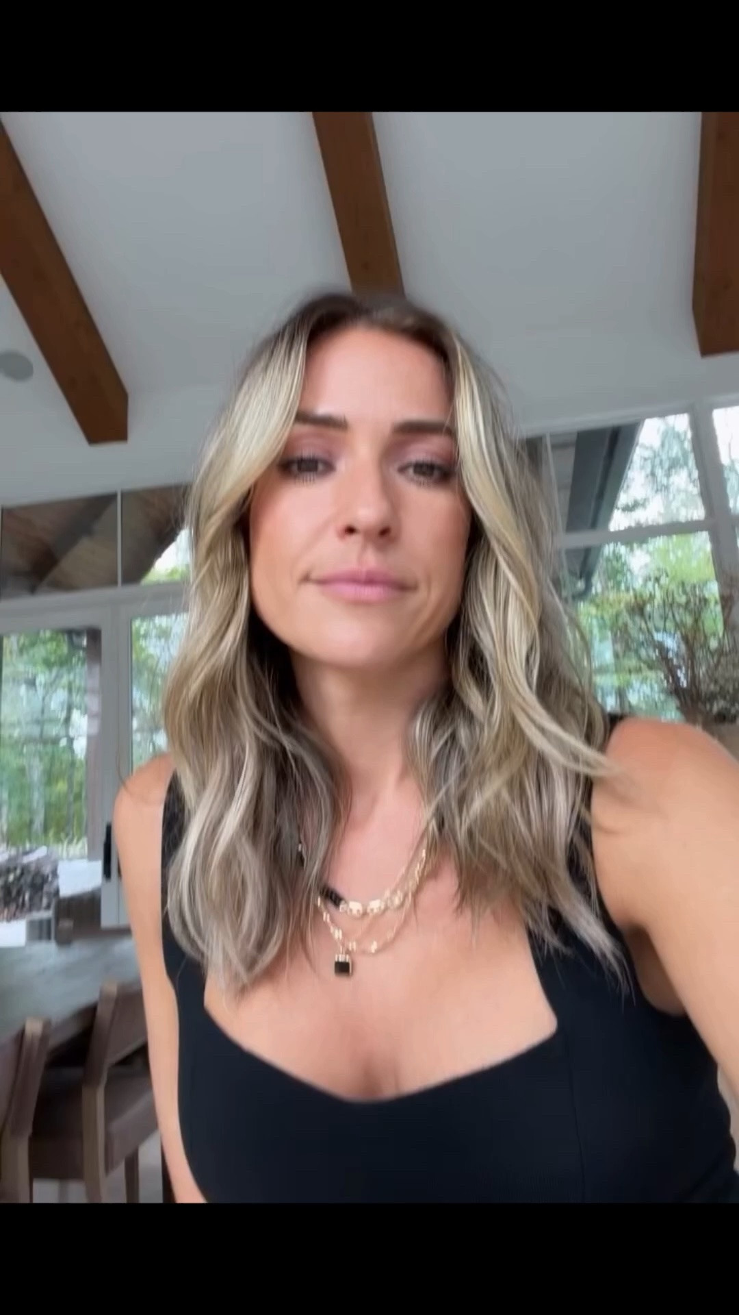 Kristin Cavallari wears a black knitted top from soft ribbed viscose in versatile black. This fitted silhouette features a cropped fit with an open neckline and thick straps. Paired with high waist black jeans with brass colored rivets