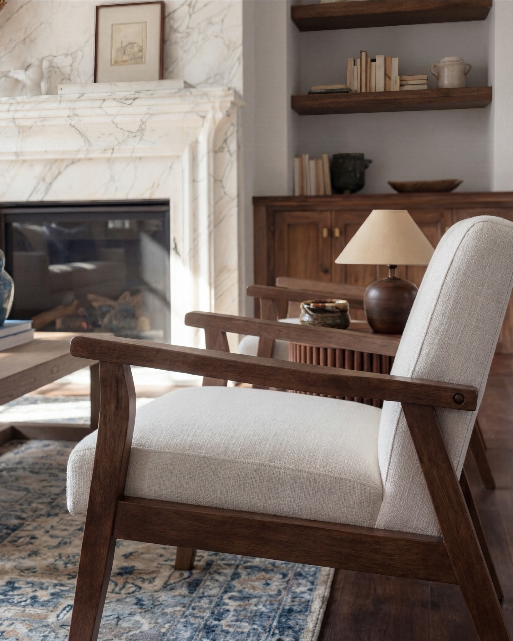 Shop the Look:
• Cream upholstered sofa (clean modern lines)
• Wood frame accent chairs with light neutral cushions
• Warm brown boucle cube ottomans
• Medium wood square coffee table
• Blue and beige vintage-style area rug
• Marble fireplace surround (white with soft veining)
• Dark wood ceiling beams
• Round wood fluted side tables
• Small ceramic table lamps (warm neutral base)
• Blue ceramic decorative vase
• Neutral textured throw blanket (warm brown)
• Blue linen accent pillows
• Floating wood wall shelves
• Wood storage cabinet with brass bird knobs
• Abstract neutral wall art (warm brown tones)
• White globe pendant light

#LTKhome #LTKsale #LTKstyletip
