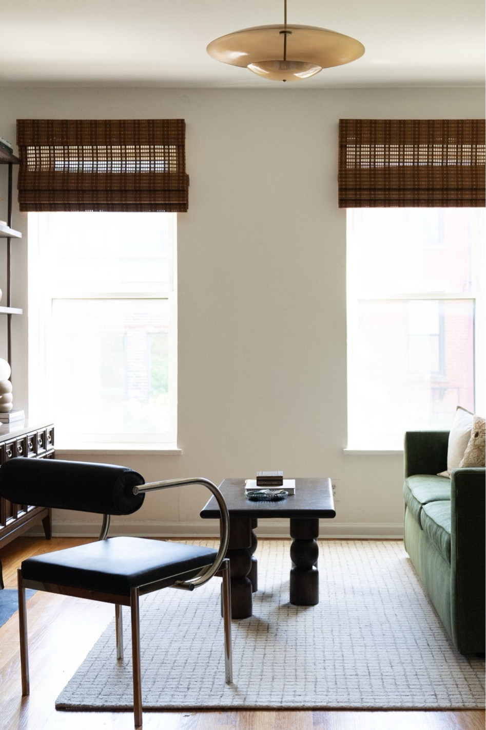 Modern apartment, bamboo roman shades, green sofa, leather and chrome chair, funky coffee table, wood coffee table, nuetral area rugg, brass semi flush mount, brass light fixture

#LTKStyleTip #LTKHome