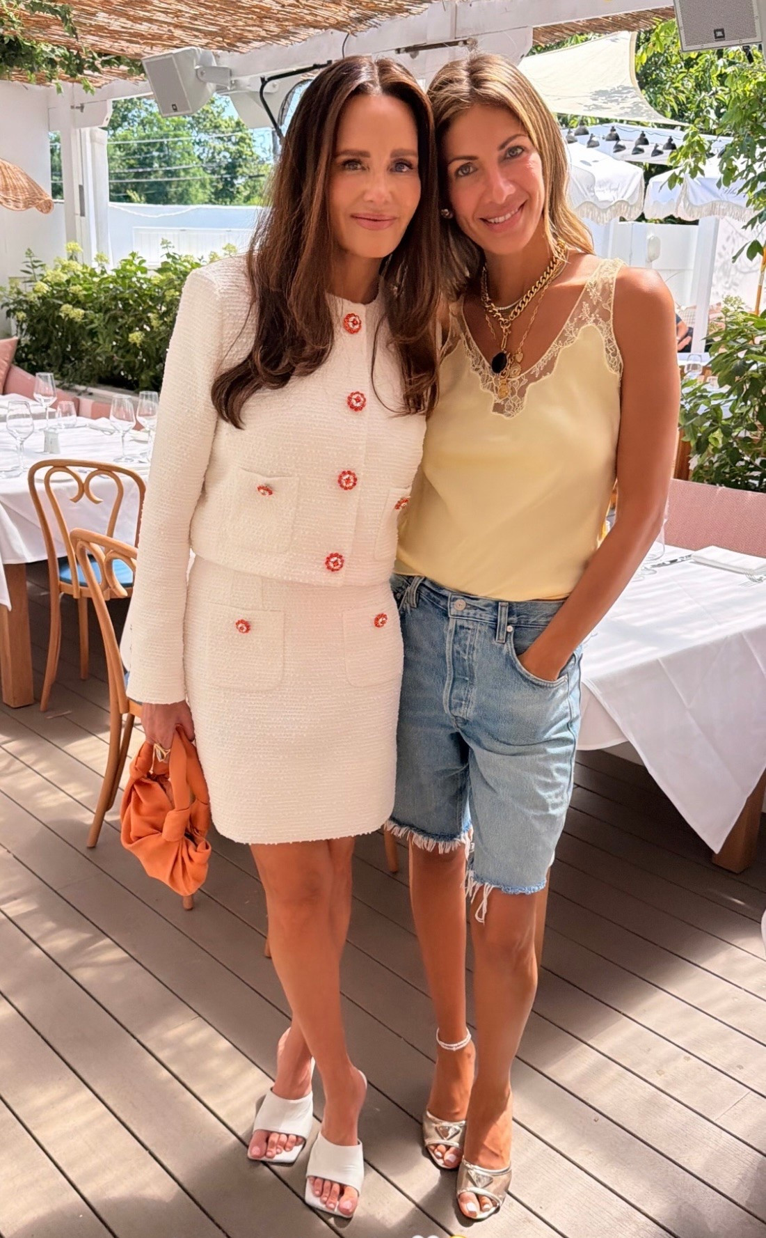 Erin Lichy wears a Satin camisole top with a round neckline and wide straps. Matching lace appliqué detail. Straight hem and Bermuda long denim jean shorts triangle logo mesh slide sandals