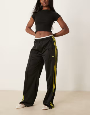adidas Originals Firebird Loose track pants in black and yellow | ASOS (Global)