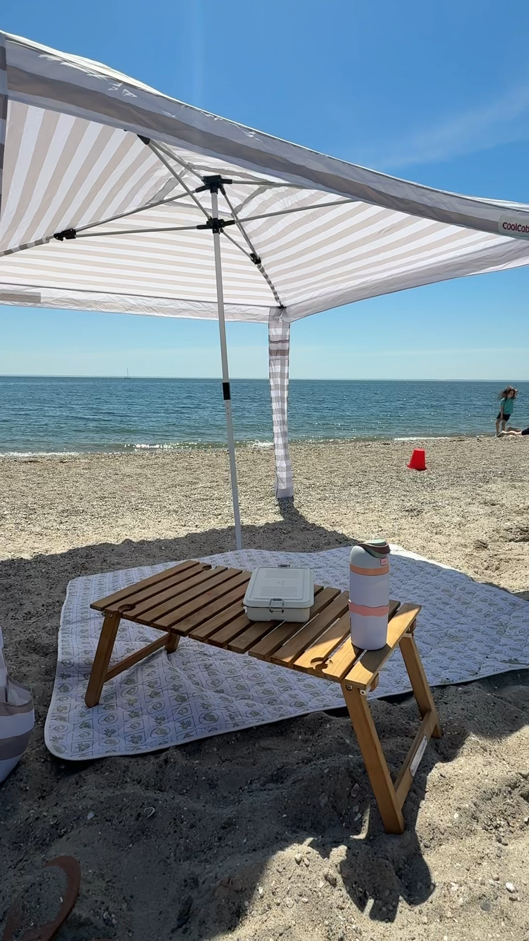 Beach set up 🏖️:
•Cool Cabana - size large 
•table on sale, 20% off. legs fold under and has a shoulder strap attached to easily carry. also has a center hole you can place umbrella through
•Stanley tin comes in 3 sizes, this is the smallest.
•beach blanket folds up into a small carry size. use code: SPRING10