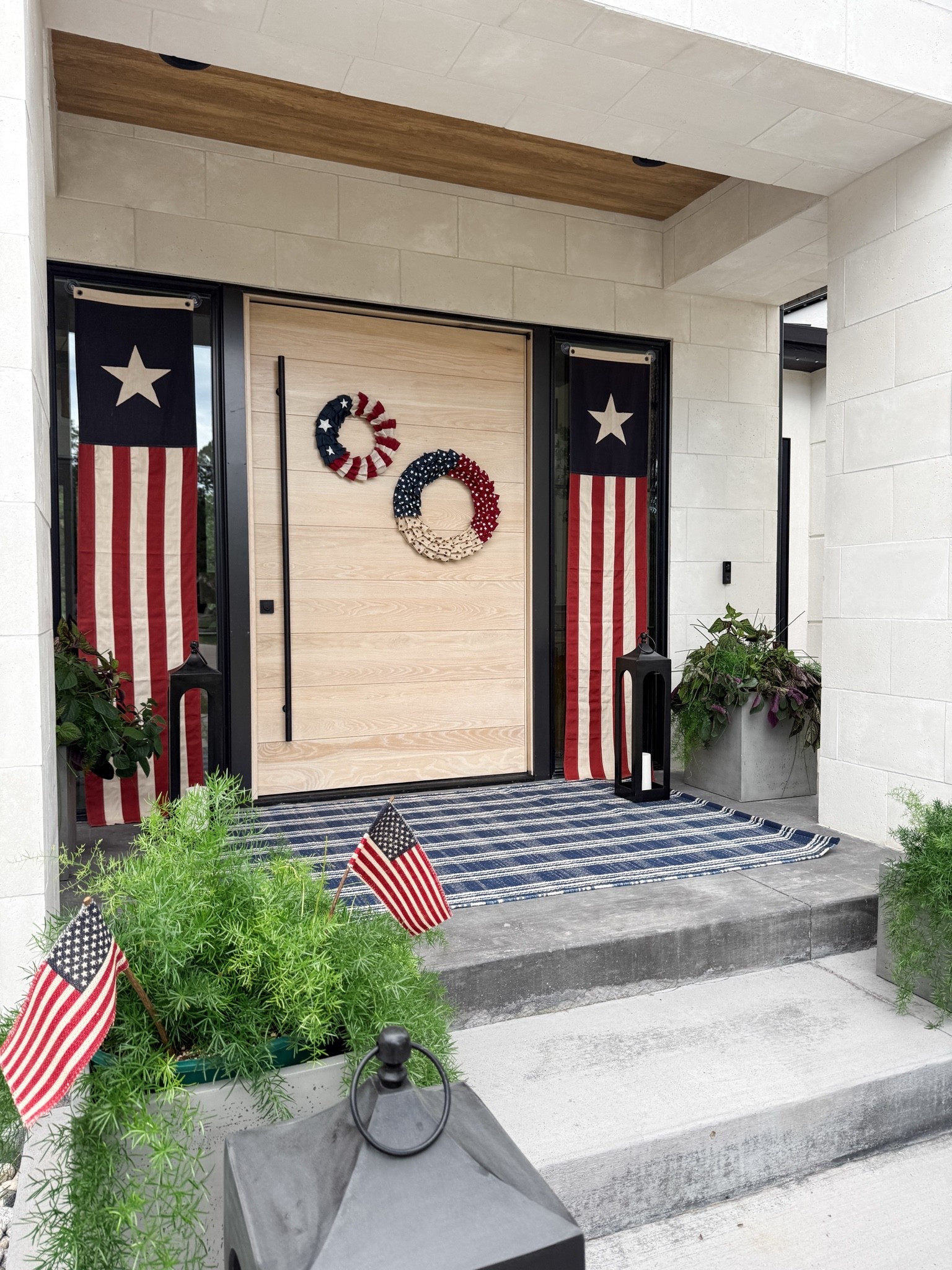 Red, white, and blue porch decor! Added some smaller flags in the planters. Double wreath moment on the front door. Made from burlap. Fourth of July.