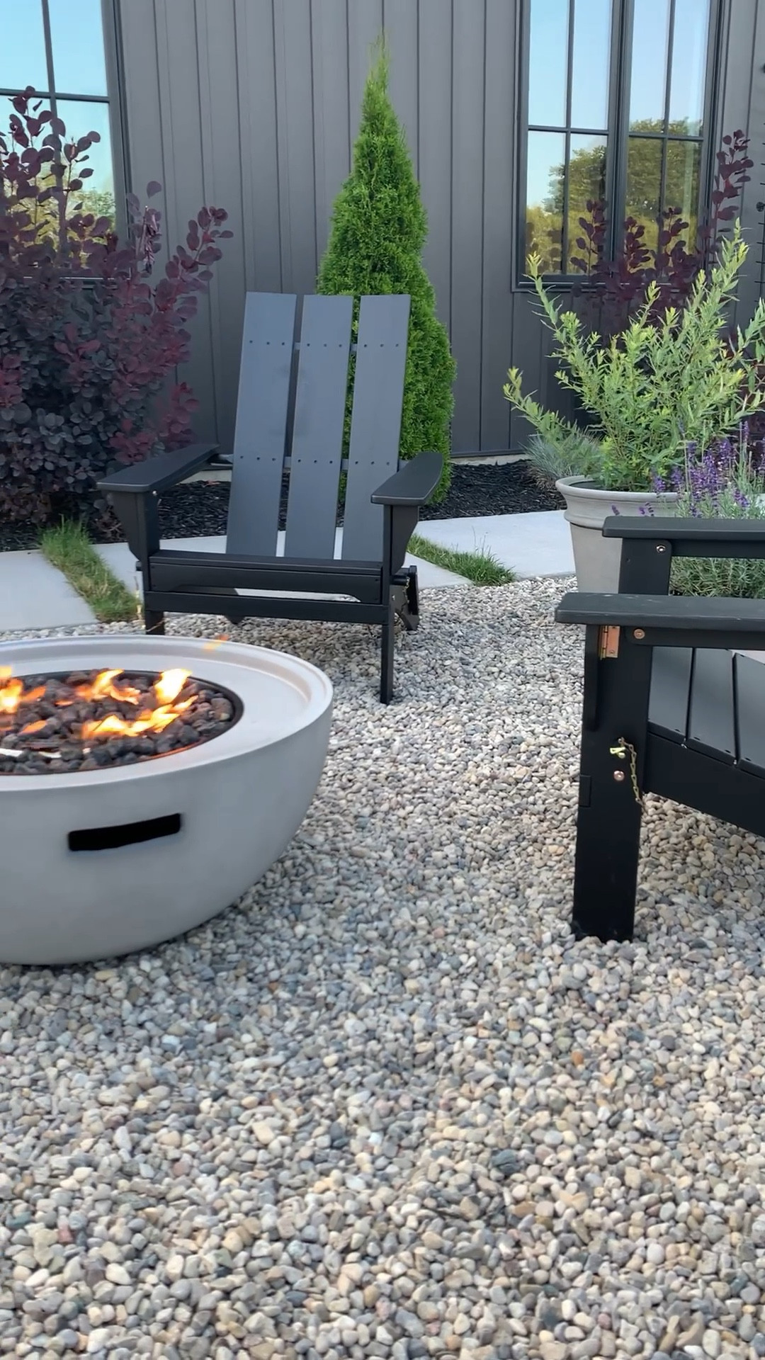 Outdoor patio sitting area. Concrete fire pit with modern Adirondack chairs 
