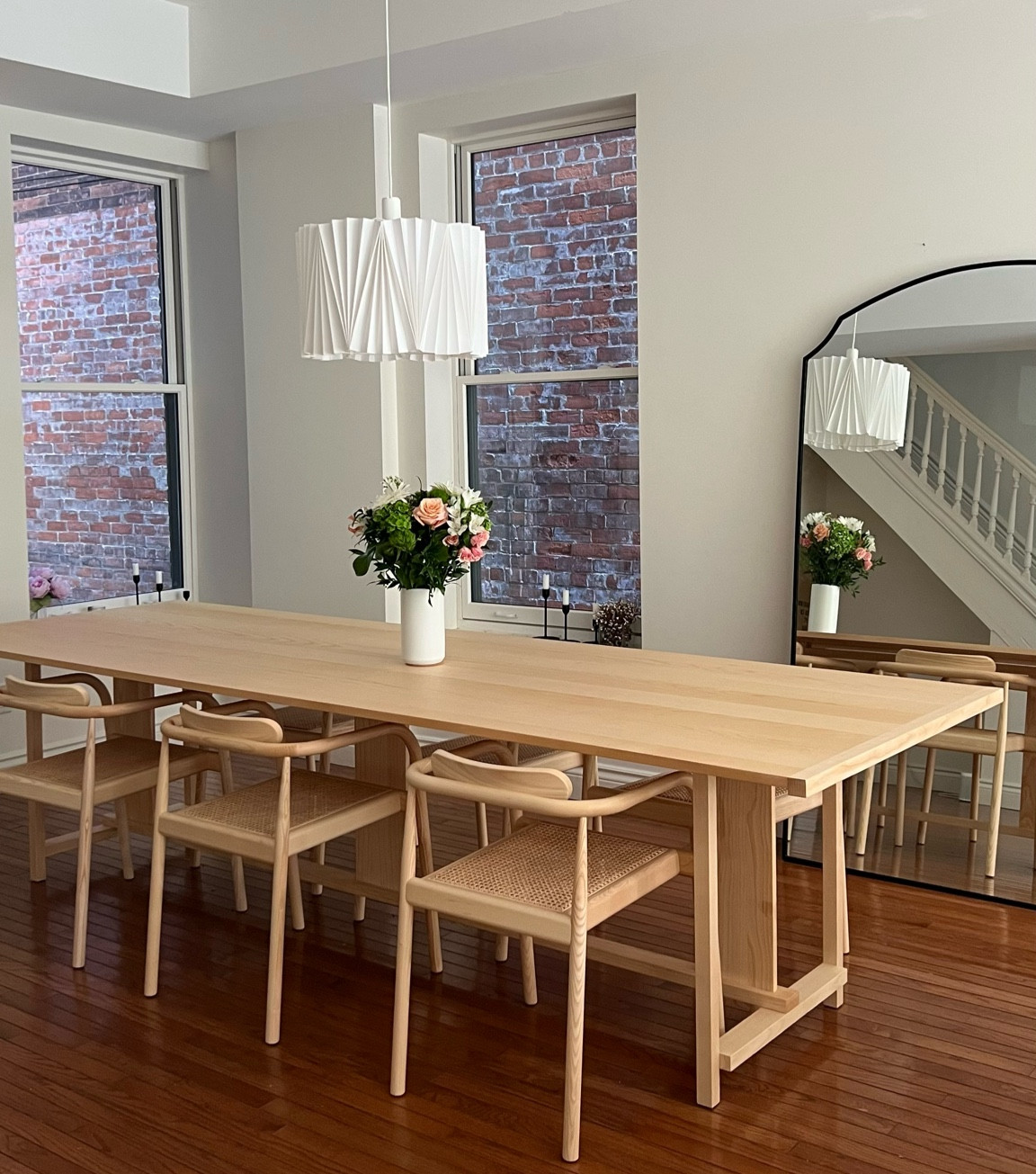 Ash table and cane dining chairs with black oversized floor mirror