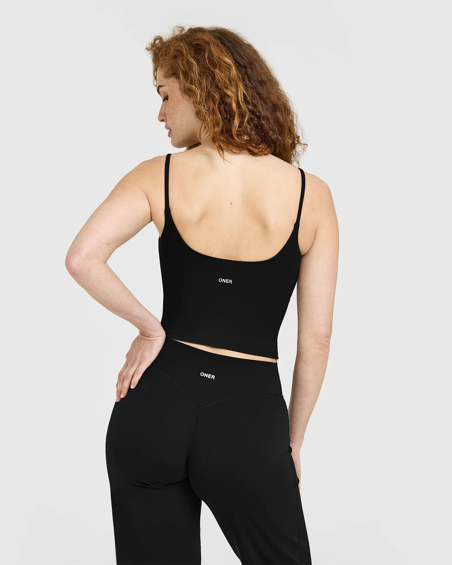 SoftMotion™ Strappy Mid Tank Top with Built in Bra Shelf with White Logo 
 Black | Oner Active (UK / US)